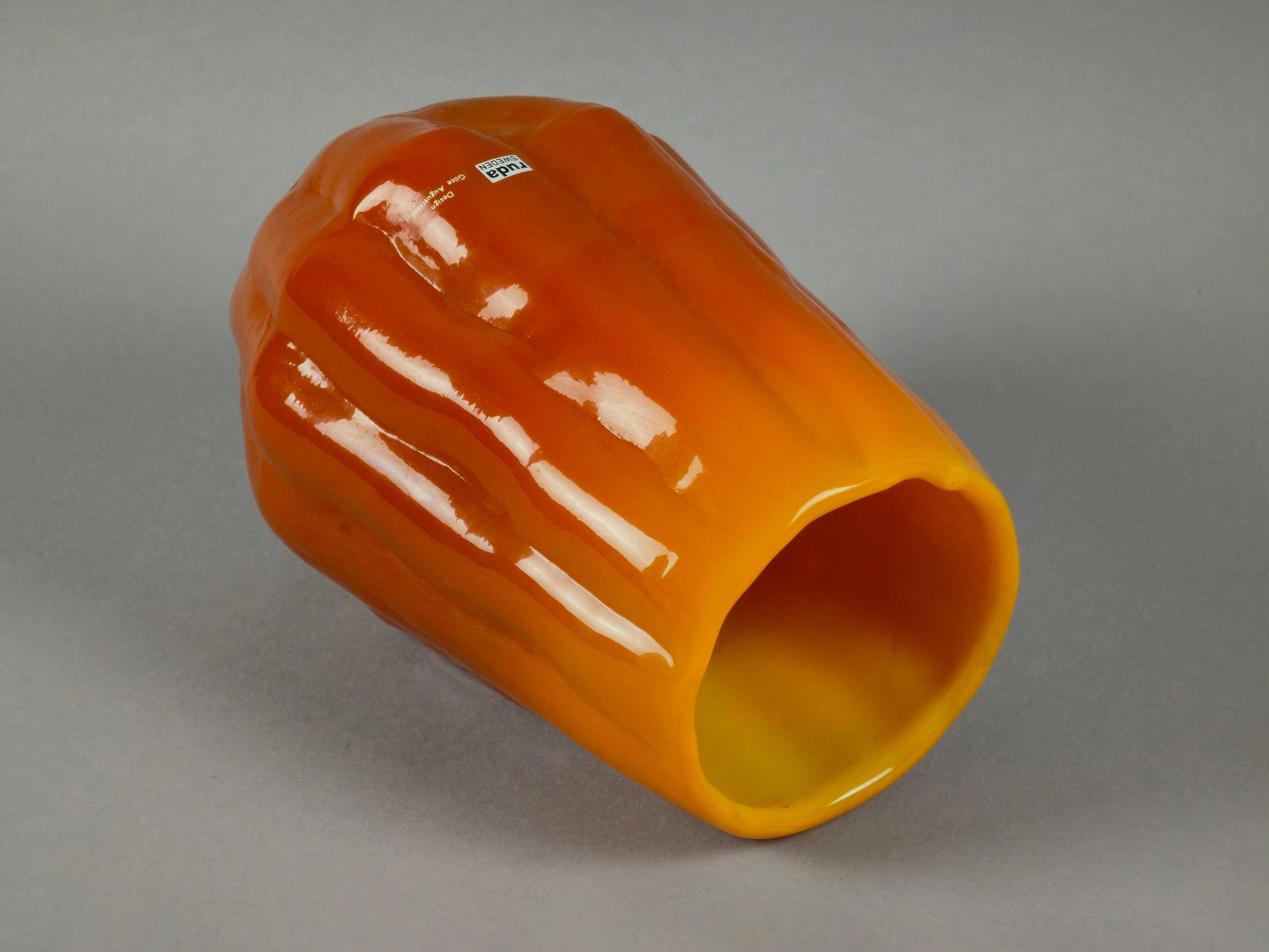 1960s vintage Ruda Glasbruk Selena vase by Gote Augustsson in orange and yellow hue, here the vase is laid down to show the texture and details of the surface.