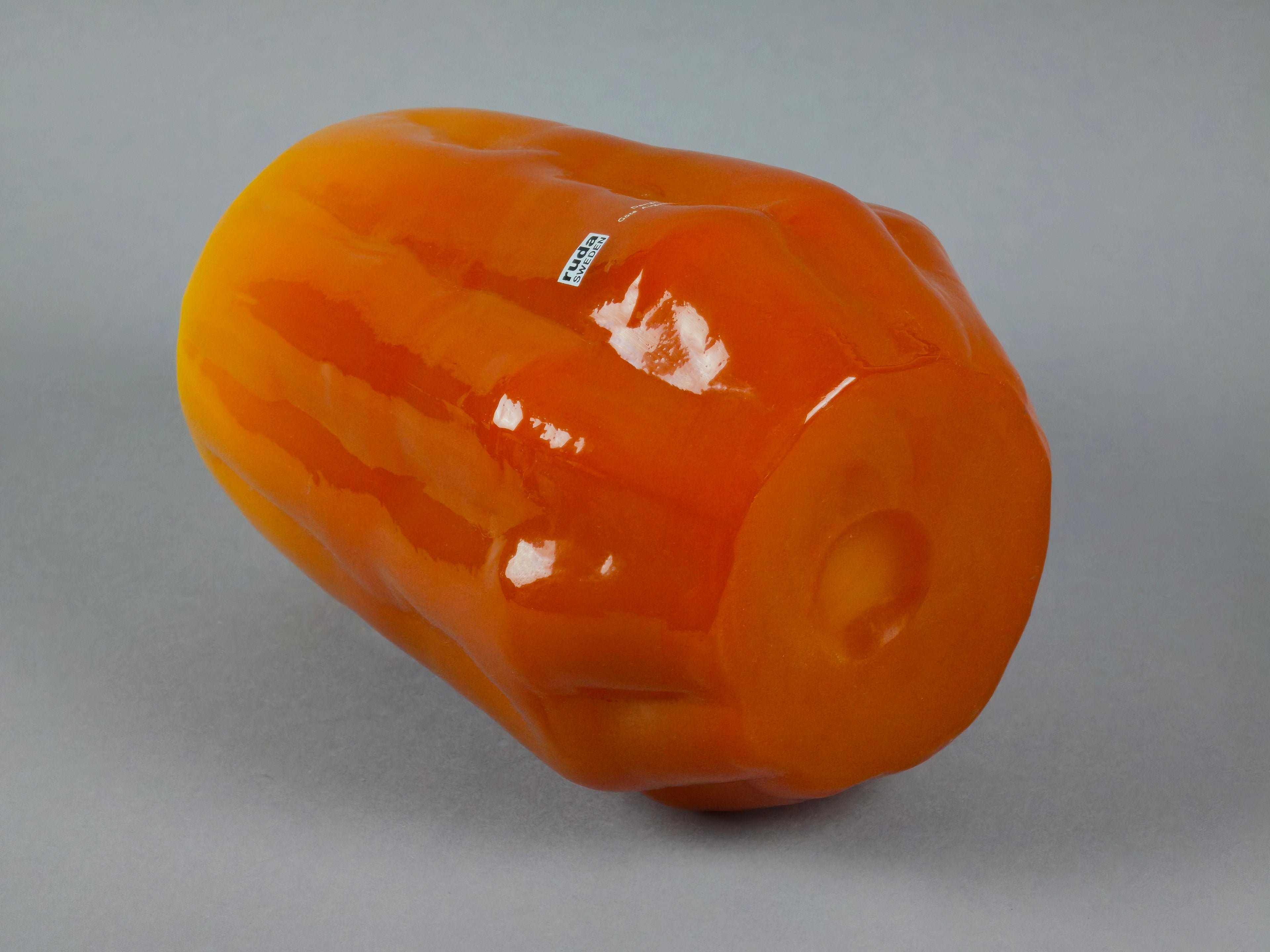 1960s vintage Ruda Glasbruk Selena vase by Gote Augustsson in orange and yellow hue, the vase is laid down to show the surface and texture of the bottom side.