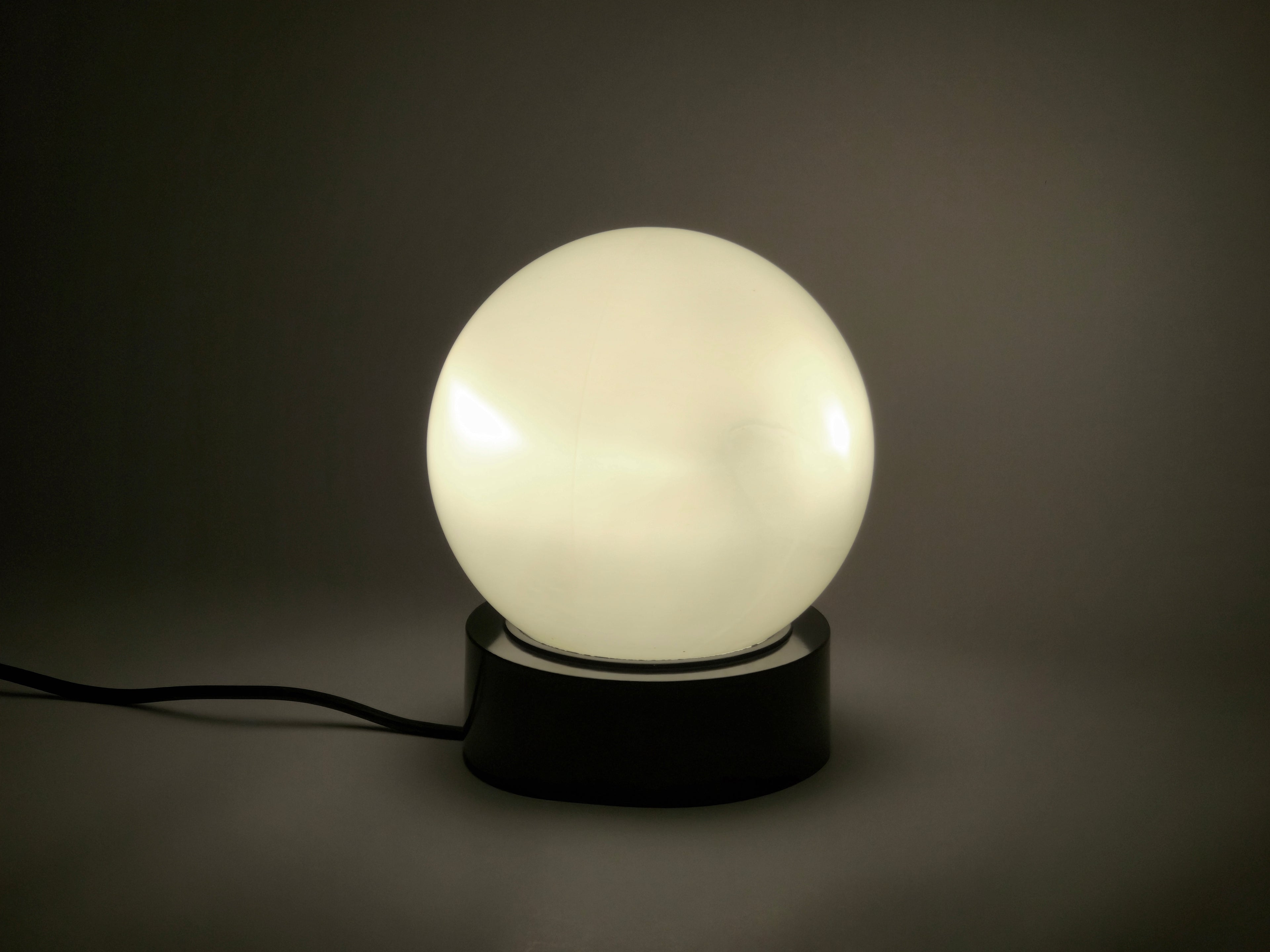 1960s vintage MCM globe glass light fixture by Corodex Holland, bird's eye view, the lamp is laid on a neutral table.