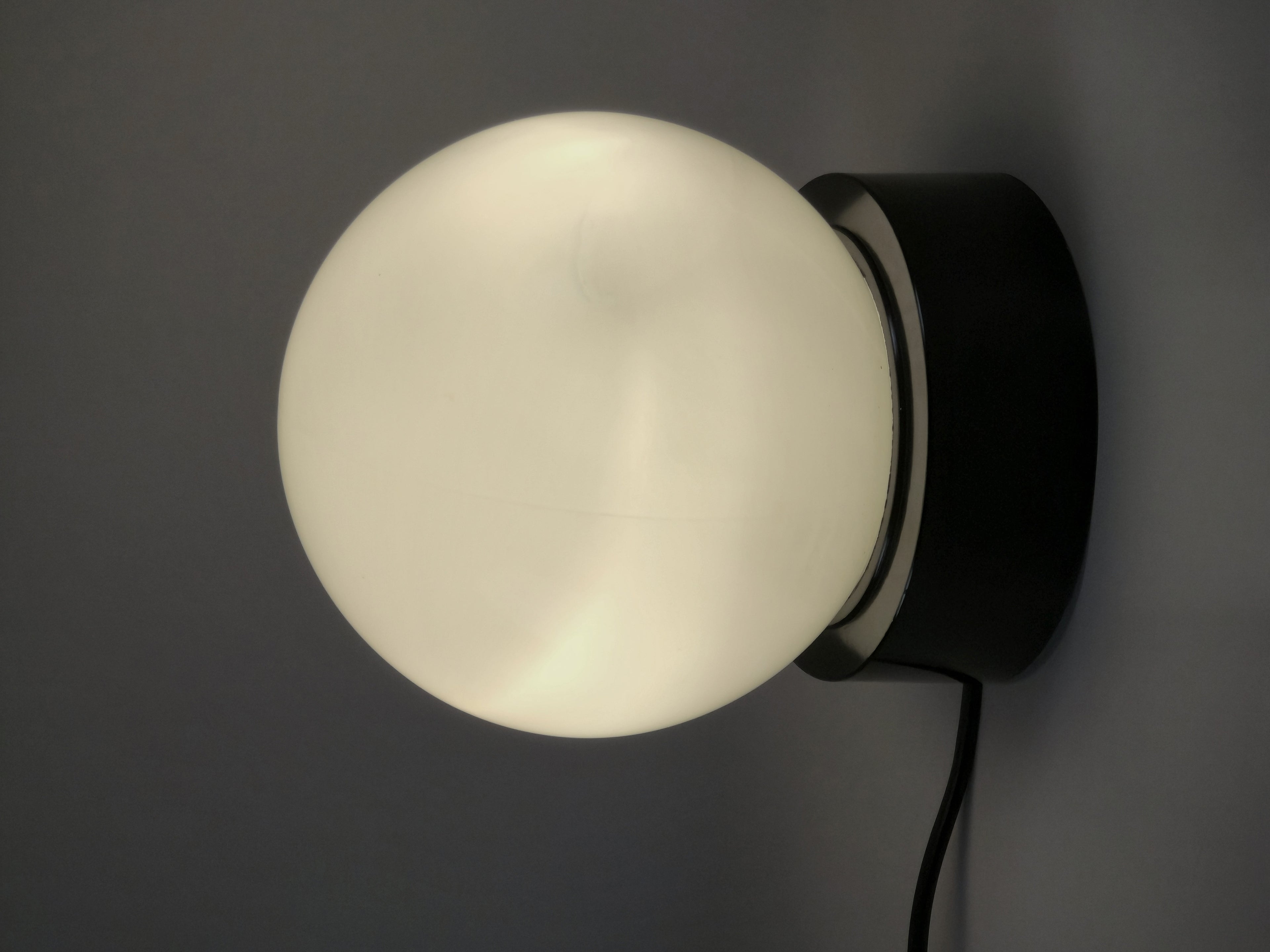 1960s vintage MCM globe glass light fixture by Corodex Holland, wall mounted and lit on a neutral background.
