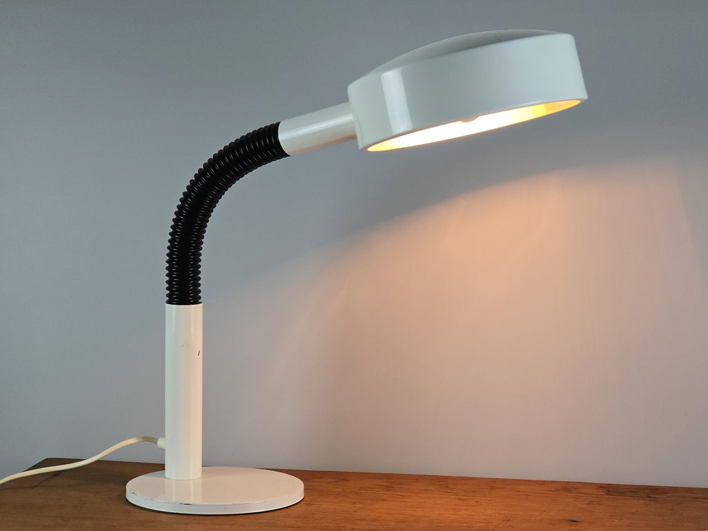 1960s Mid Century Modern gooseneck desk lamp by Hala Zeist, slightly angled profile view of the lamp lit, on a vintage wooden table.