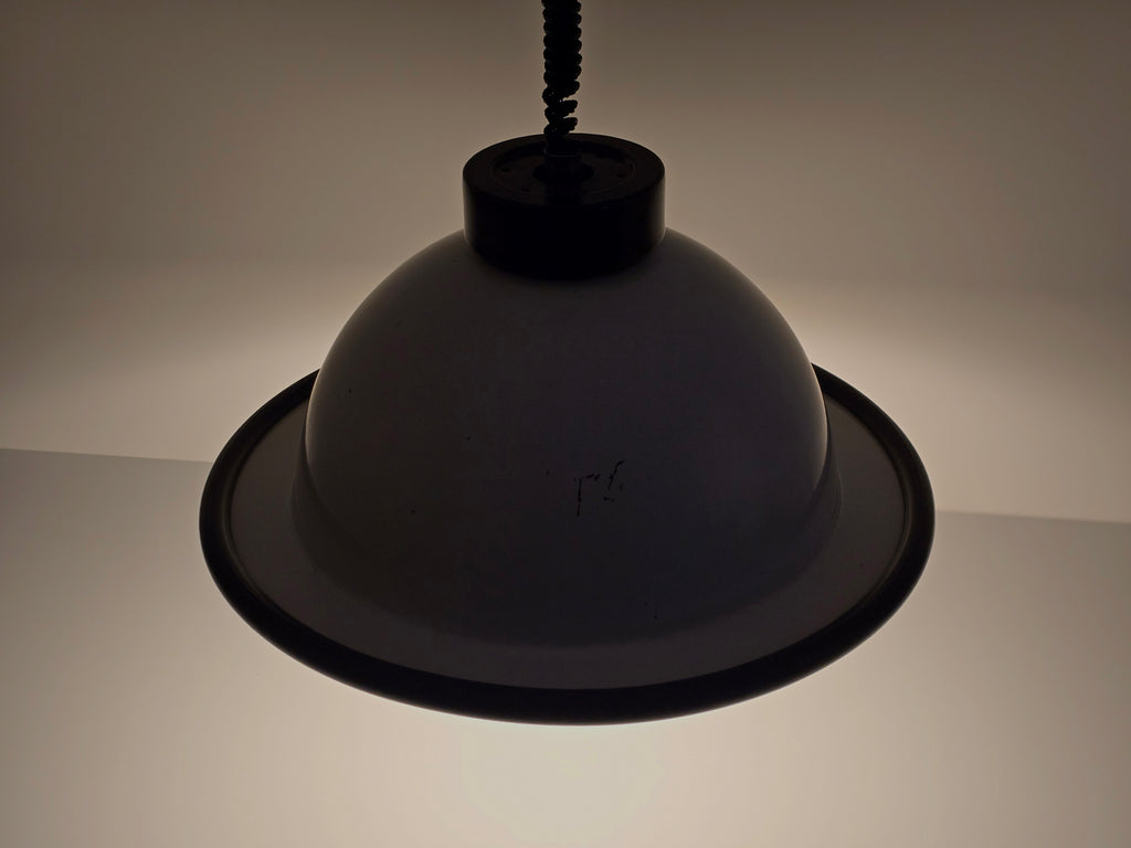 The vintage 1960s MCM Martinelli Luce rise & fall pendant lamp by Elio Martinelli shown in a darkened setting, top down view, to highlight the shape of the lamp.