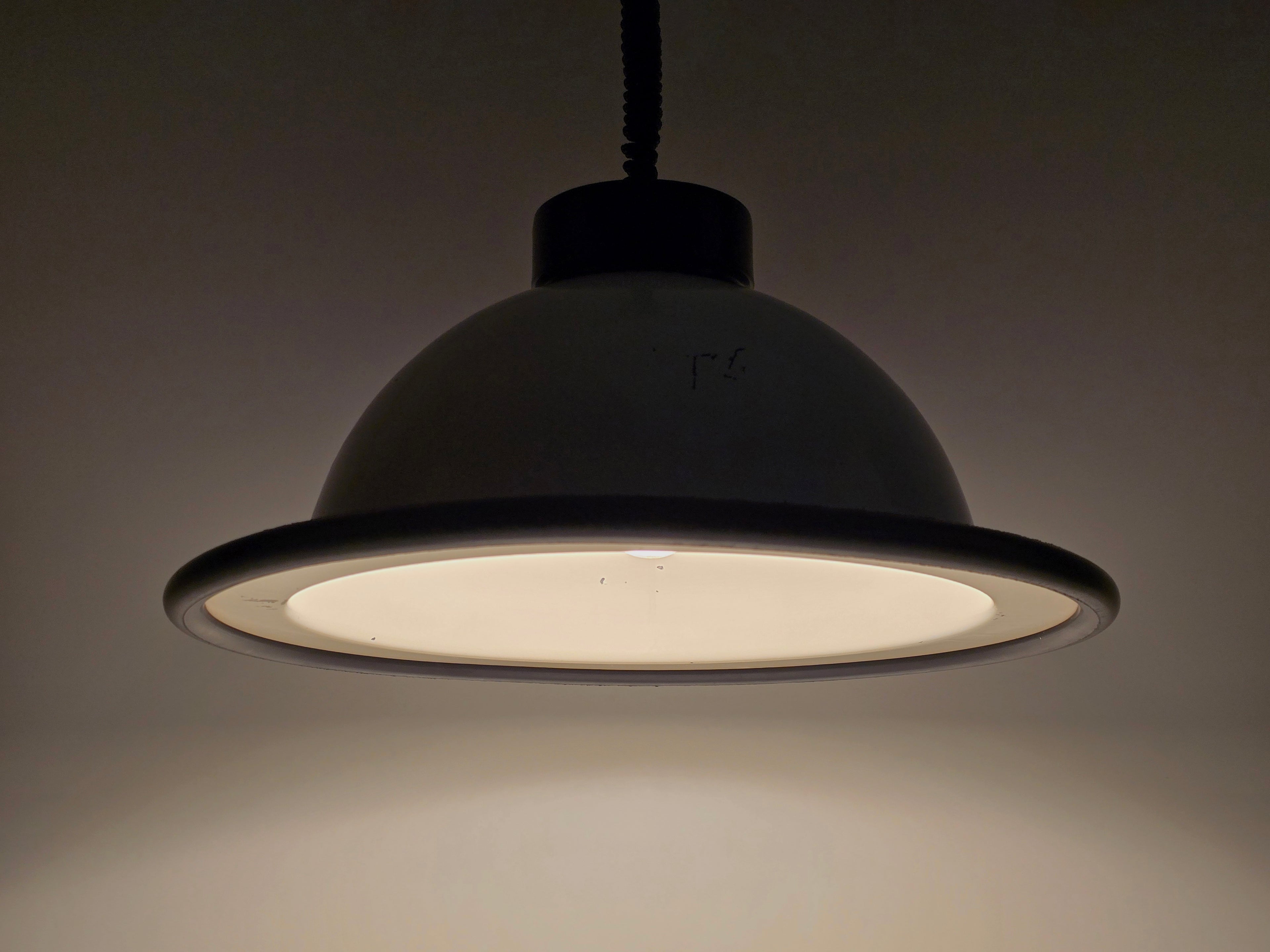 The vintage 1960s MCM Martinelli Luce rise & fall pendant lamp by Elio Martinelli illuminated to show the soft downward light diffusion.