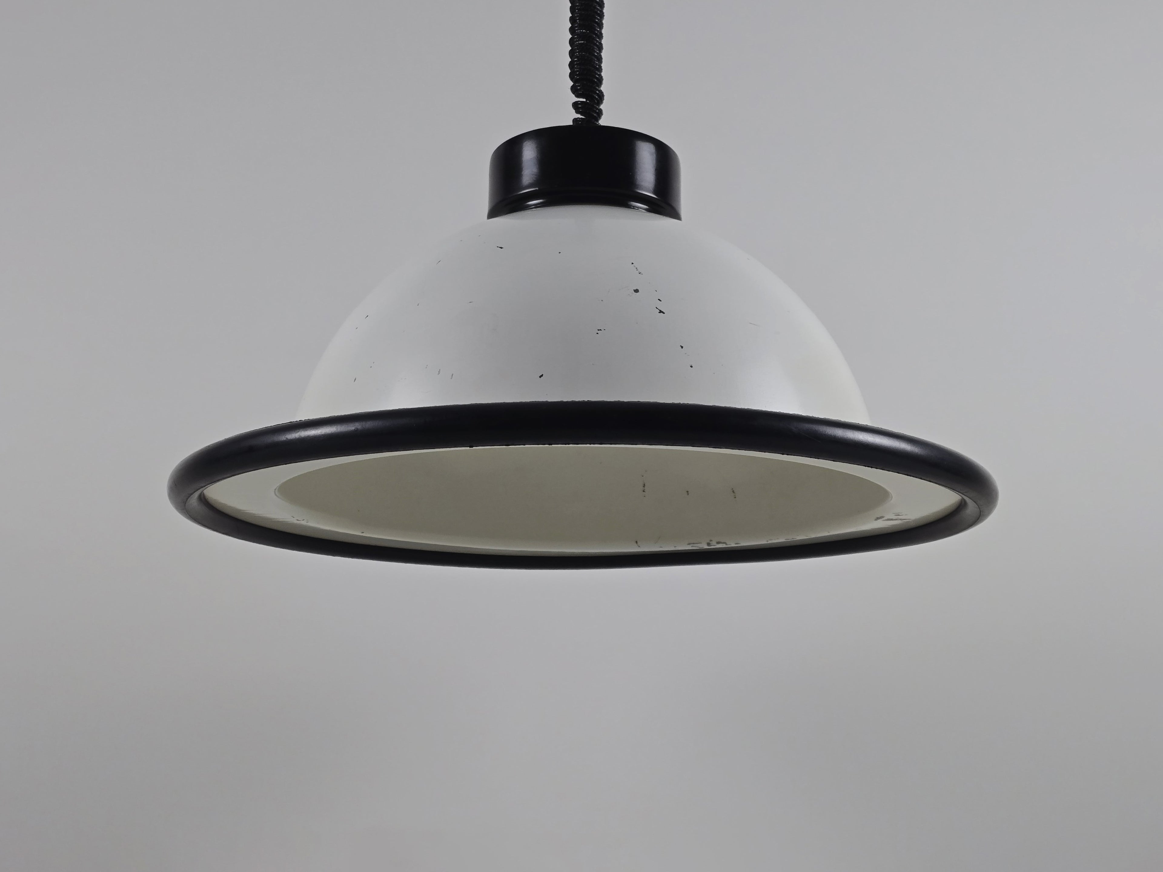 A primary studio shot of the vintage 1960s MCM Martinelli Luce rise & fall pendant lamp by Elio Martinelli, featuring a white domed shade with a black rim.