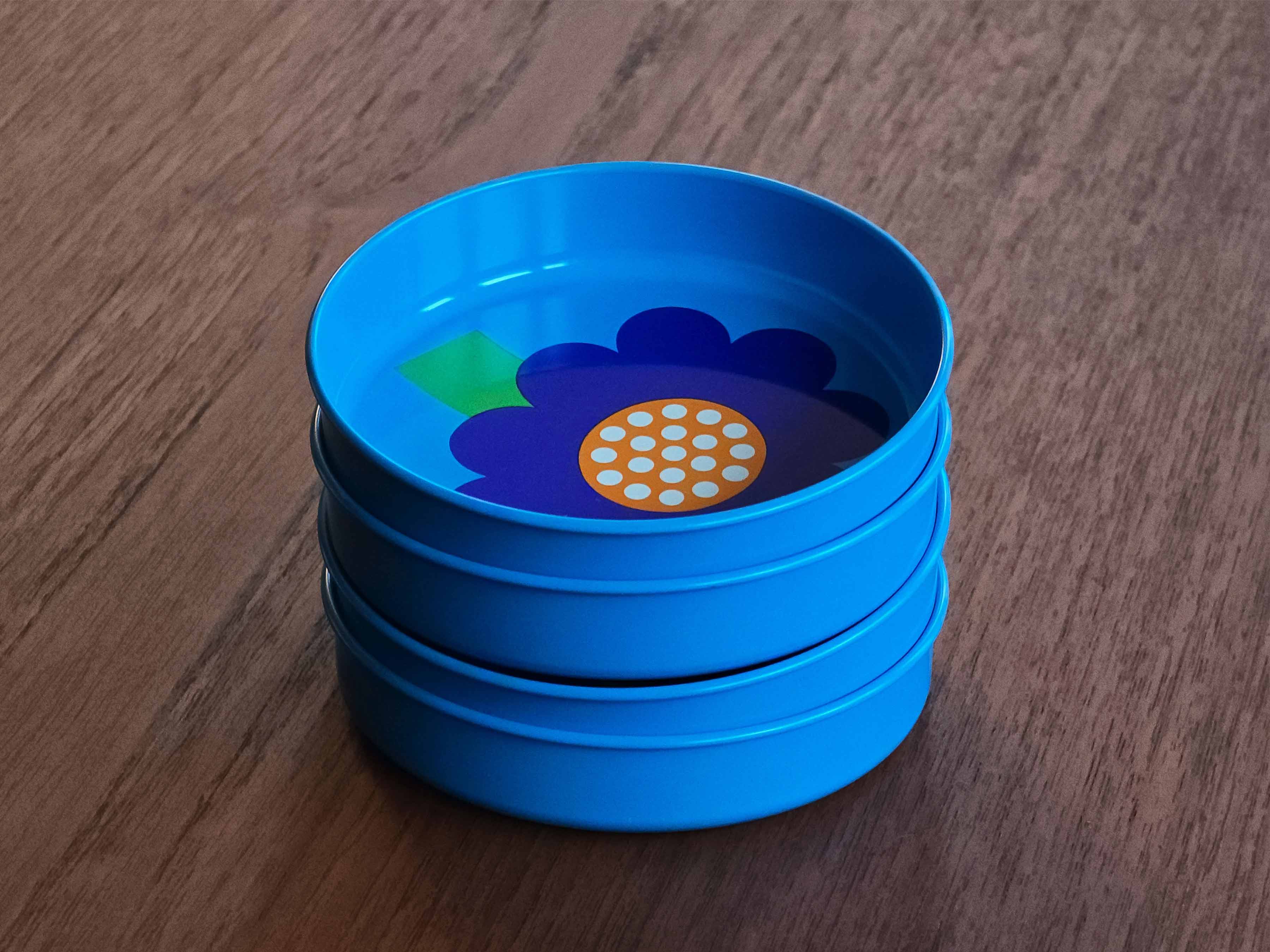 Top down perspective image of four vintage 1970s Laurids Lønborg tin trays designed by Al and Lena Eklund, stacked together on a teak table.