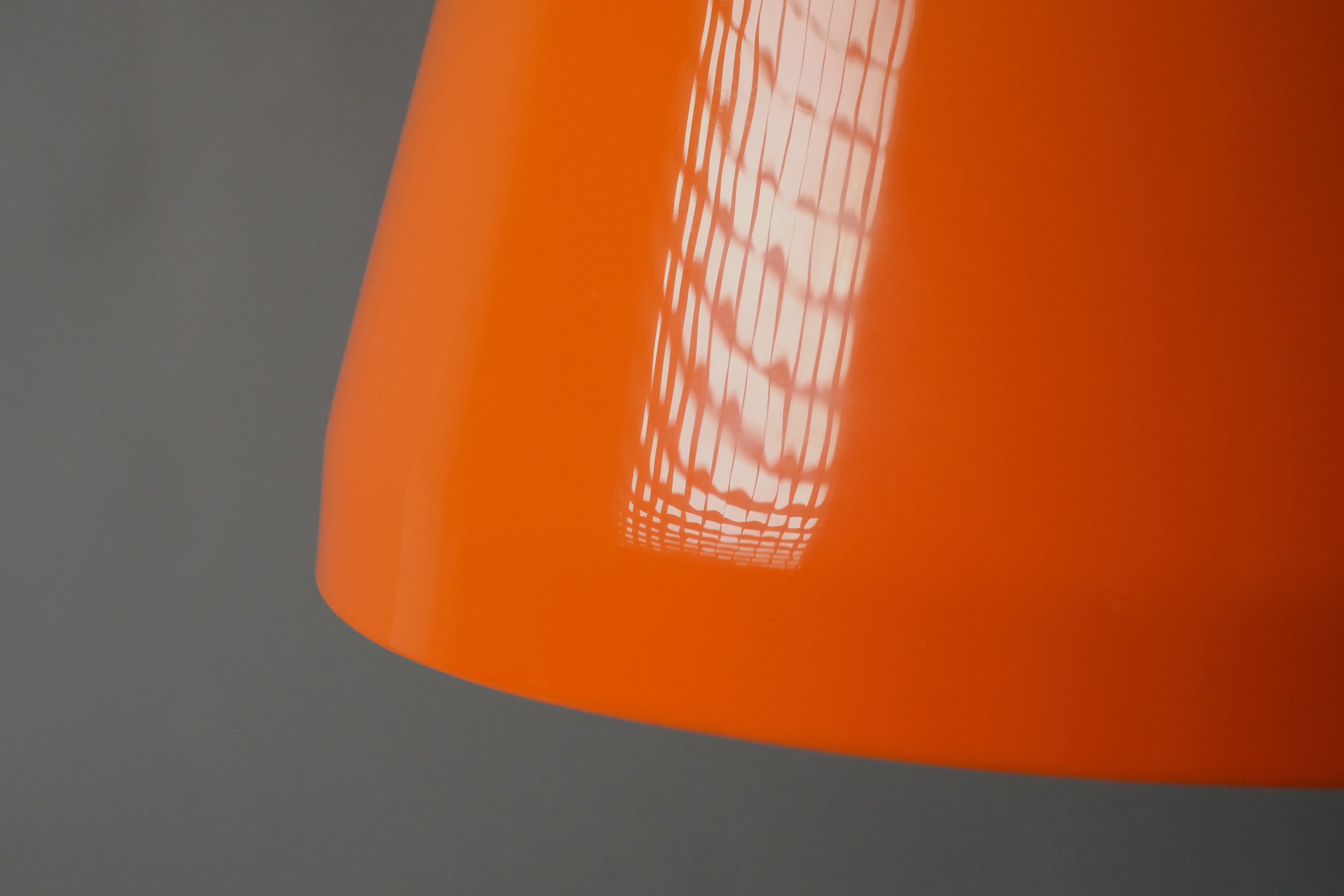 Close-up side detail of a 1970s orange acrylic Space Age pendant lamp, showing the high-gloss surface finish and consistent color saturation of the exterior acrylic.