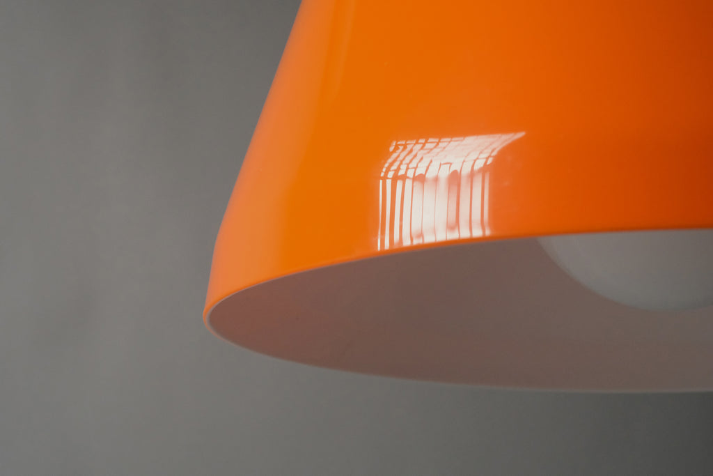 Close-up of the lower edge of a 1970s orange acrylic Space Age pendant lamp, revealing the precise bonded transition between the glossy orange exterior and white interior layer.
