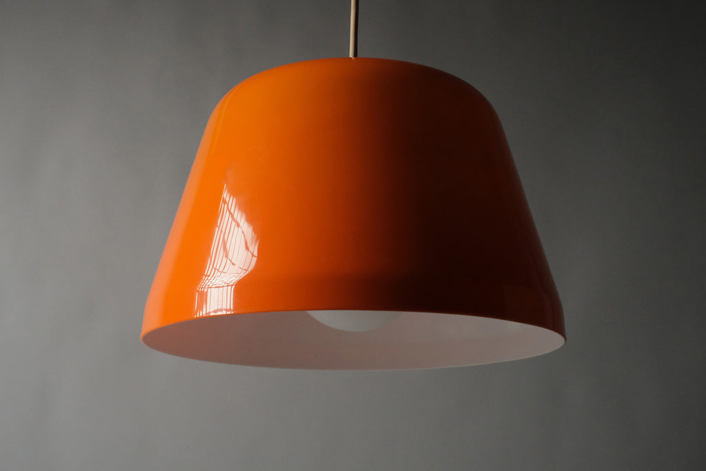 Low-angle view of a 1970s orange acrylic Space Age pendant lamp, showing the broad dome profile and the clean unobstructed opening of the white interior layer below.