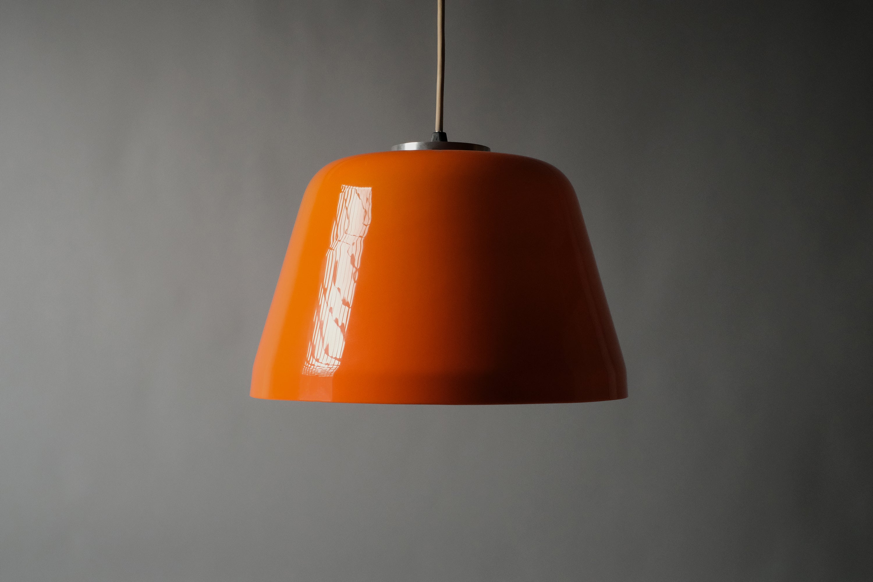 Full profile view of a 1970s orange acrylic Space Age pendant lamp suspended on cord against a neutral background, showing the complete proportions of the shade unlit.