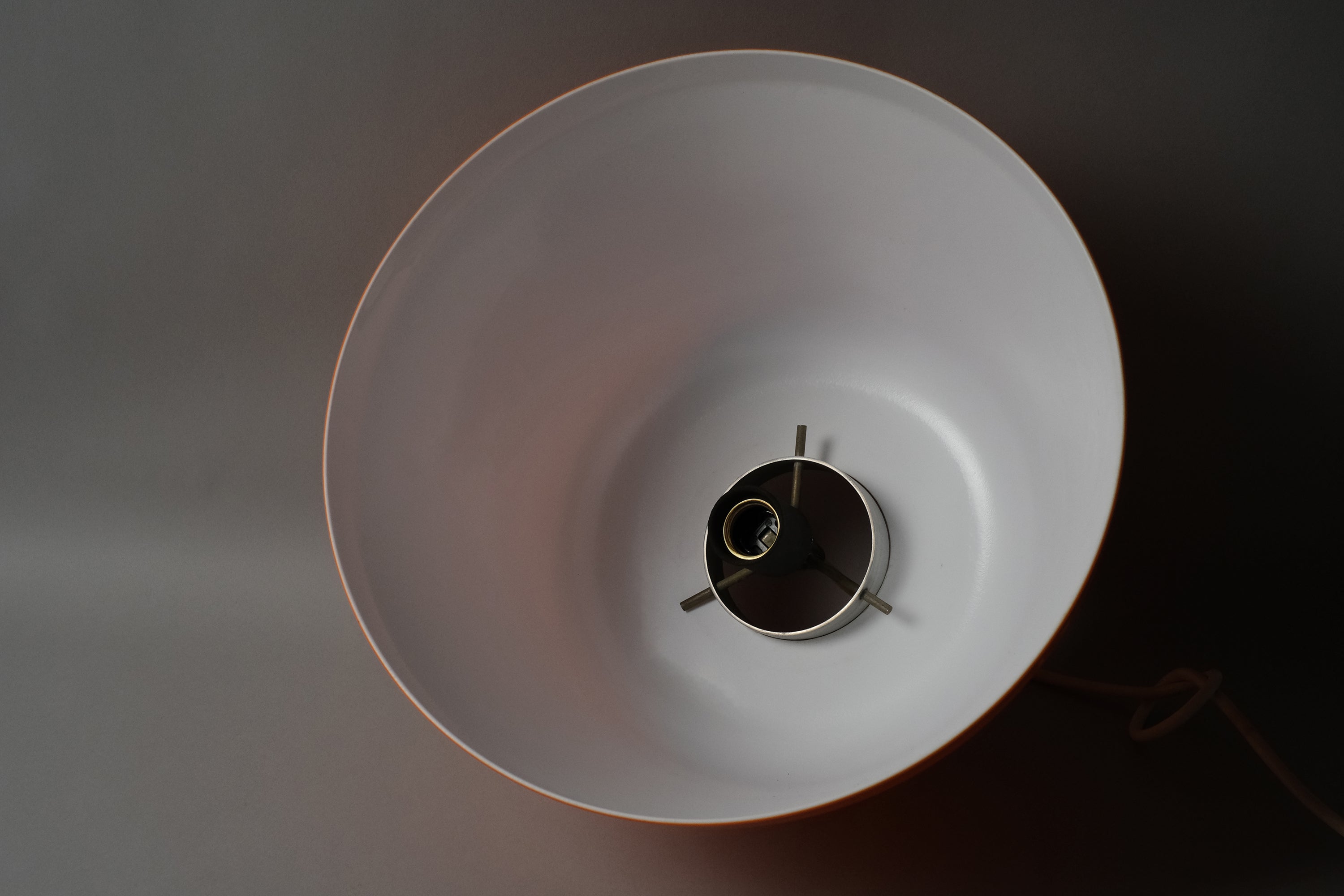 Interior view looking up into a 1970s dual-layer orange acrylic Space Age pendant lamp, showing the smooth white bonded interior surface and central E27 lamp fitting.