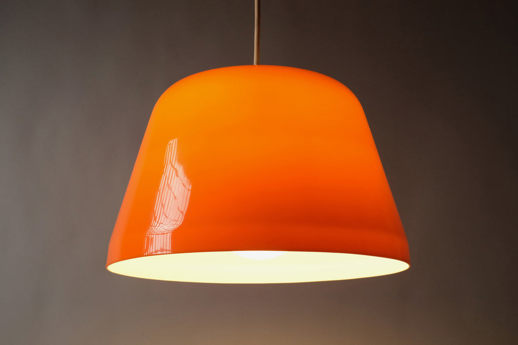 Front view of 1970s dual-layer orange and white acrylic Space Age pendant lamp, showing the clean dome silhouette with white interior, softly illuminated.