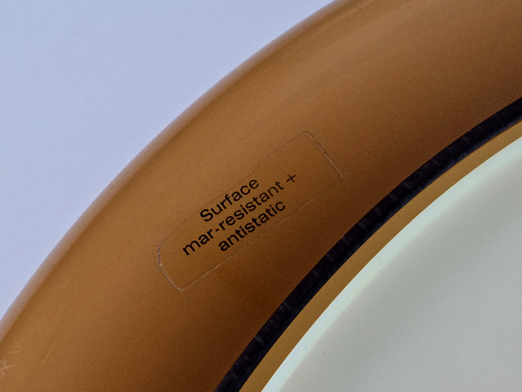 Macro detail of the authentic vintage manufacturer's stamp or label on the inner rim of the lamp. The label reads: 'Surface mar-resistant + antistatic'.