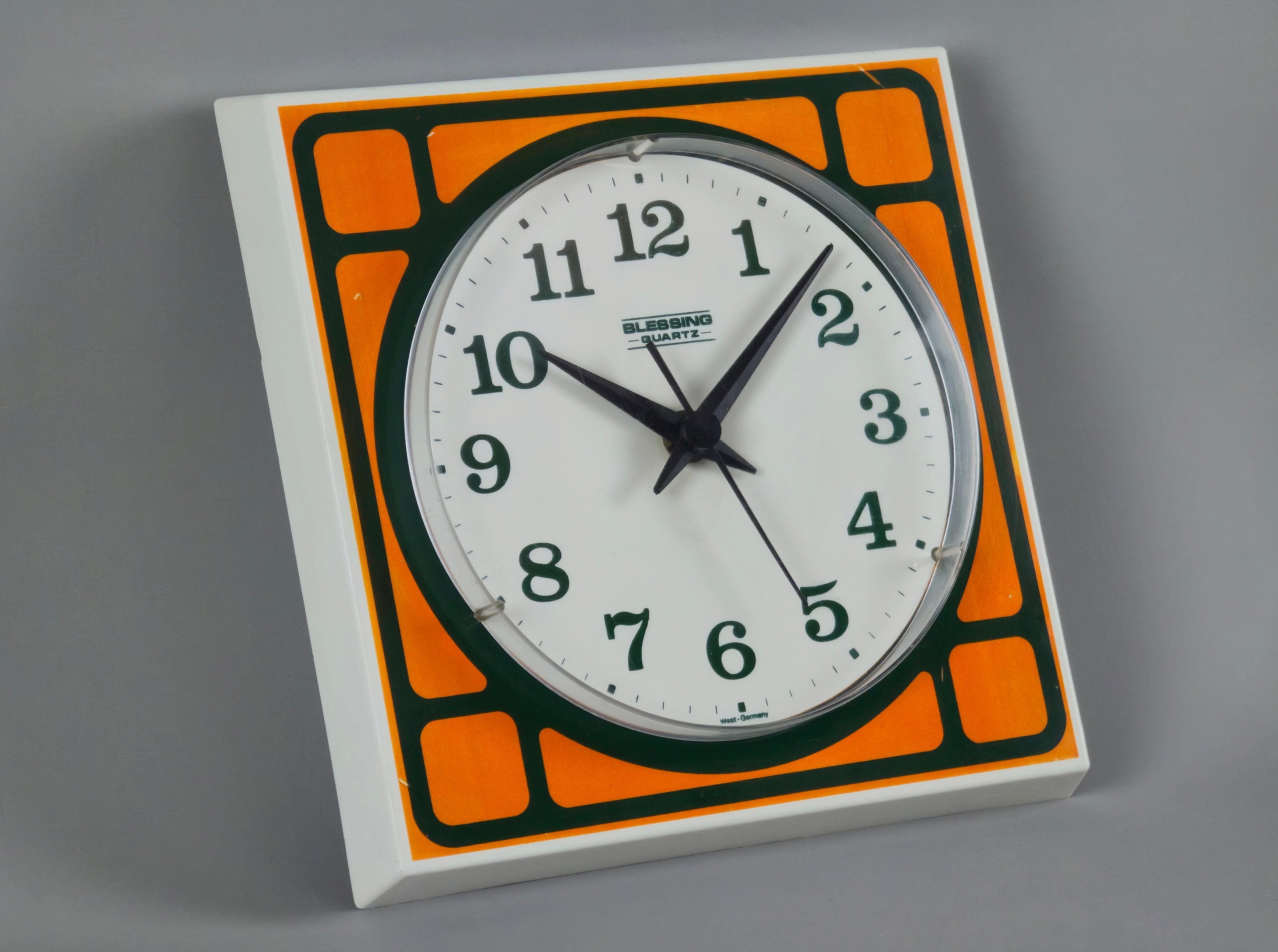 1970s Space-Age Design Blessing orange plastic wall clock, angled view showing the face and depth of clock.
