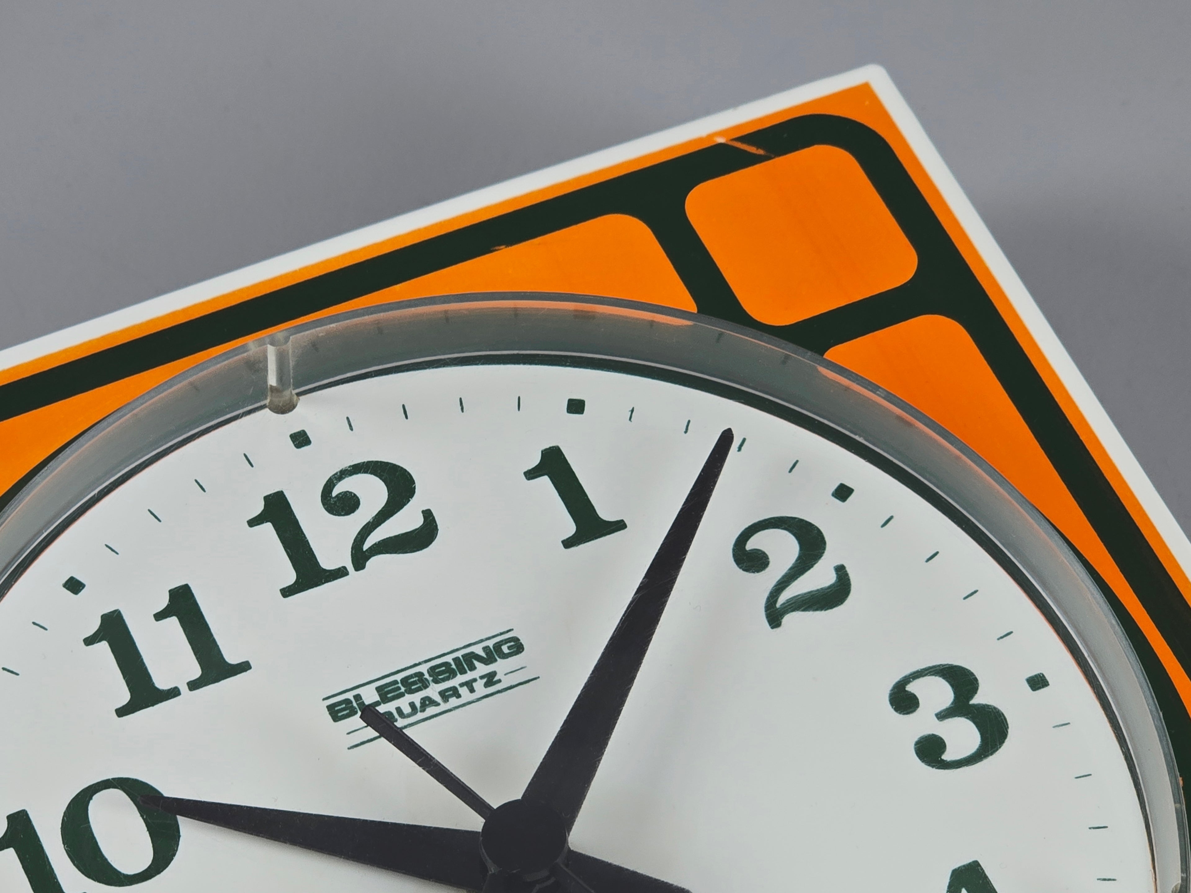 1970s Space-Age Design Blessing orange plastic wall clock, macro shot showing the branding of the clock 'Blessing Quartz'.