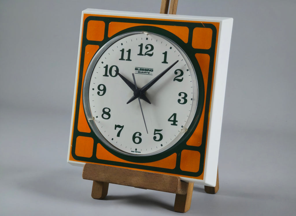 1970s Space-Age Design Blessing orange plastic wall clock, angled profile of clock on a vintage wooden stand.