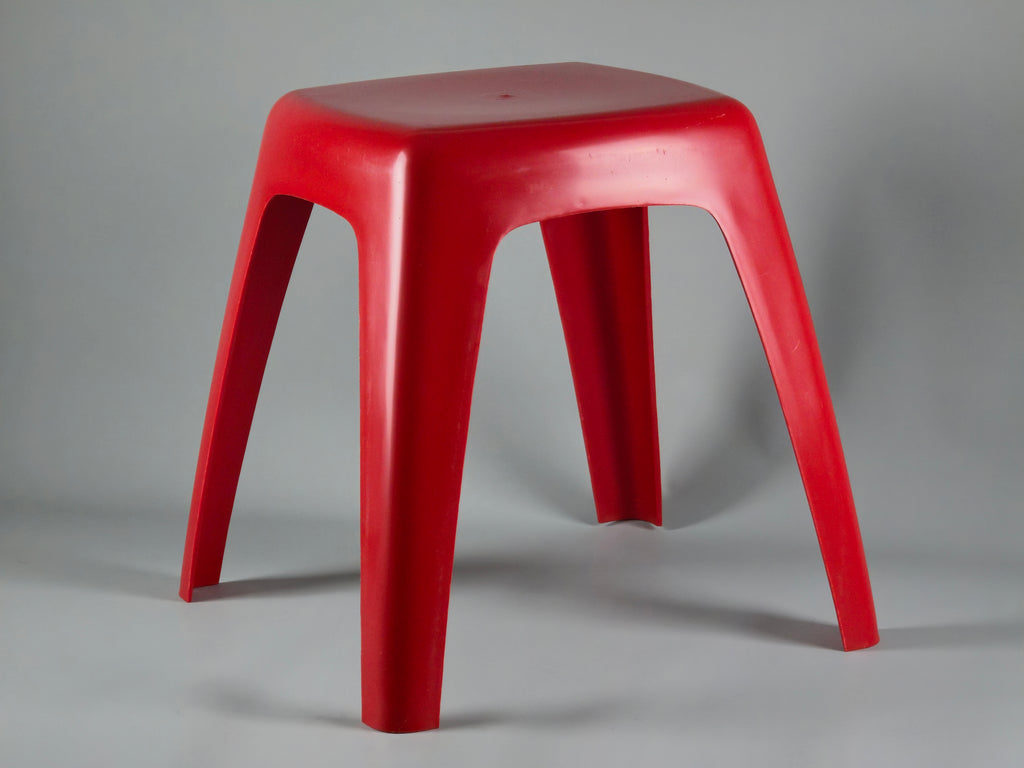 Vibrant red 1970s plastic stool by Flair Holland. Smooth, glossy hourglass shape with a minimalist Space Age silhouette. Shown from the front against a clean, neutral background.
