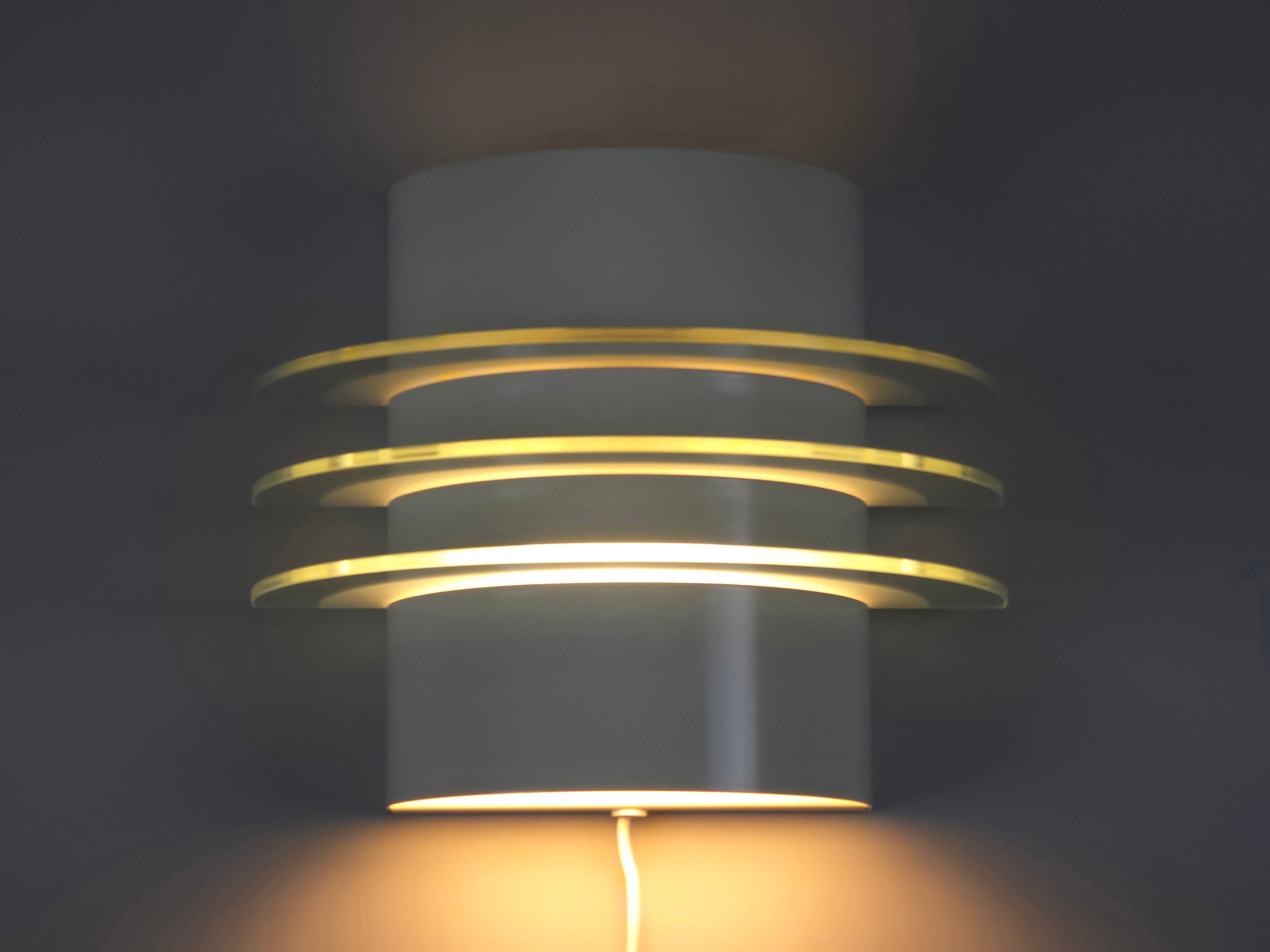 IKEA Drittel wall lamp illuminated, showing the warm tiered light glow diffused through three glass plates.