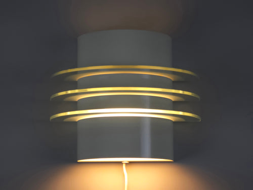 IKEA Drittel wall lamp illuminated, showing the warm tiered light glow diffused through three glass plates.