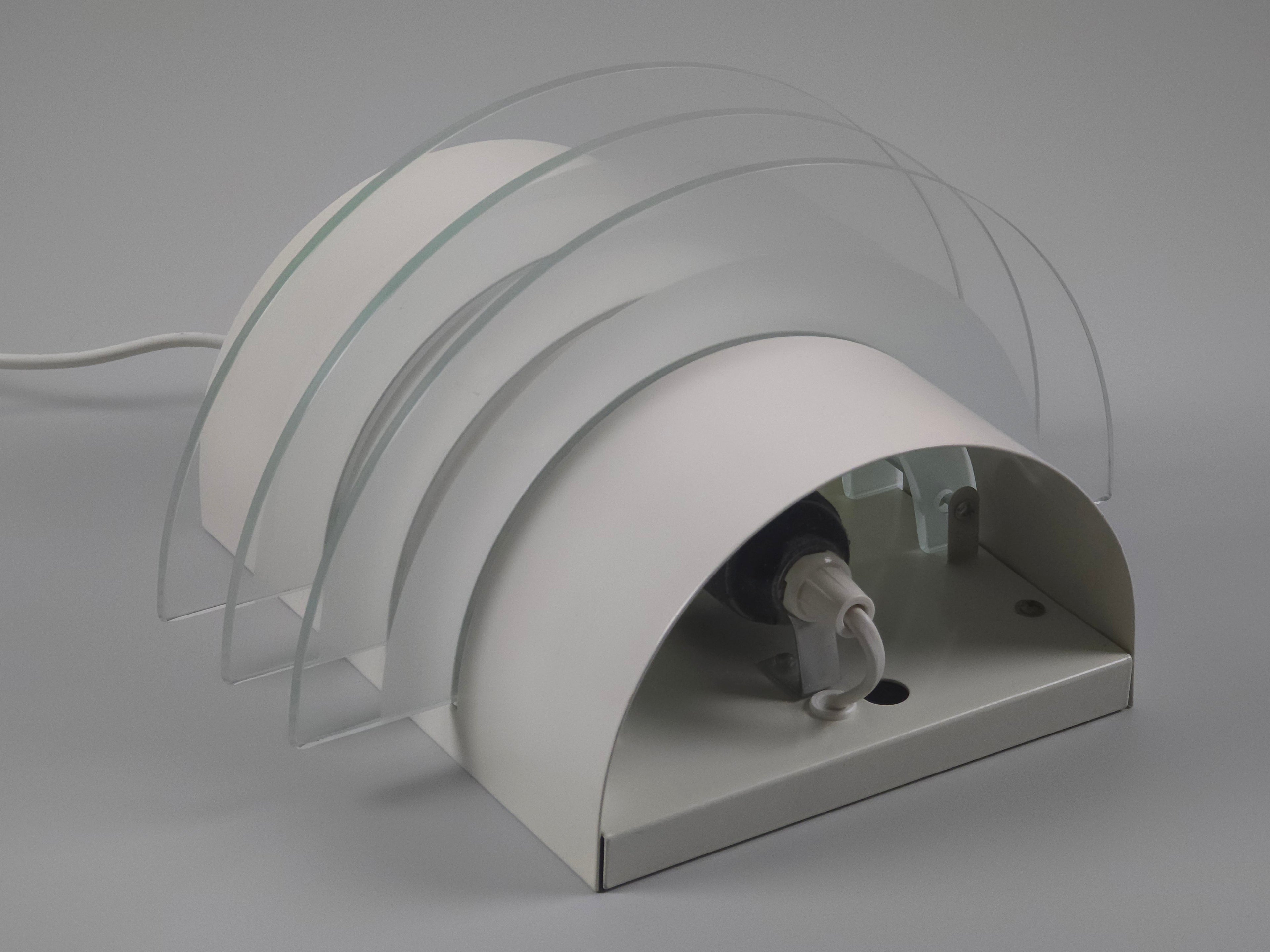 Underside view of the Drittel sconce illustrating the semicircular wall mount and light-filtering glass tiers.