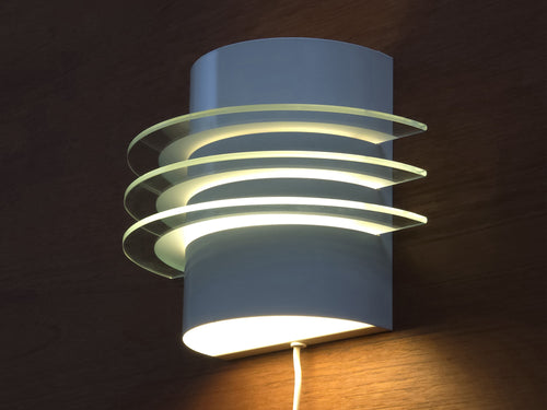 Wall mounted view of the Drittel sconce illustrating the semicircular wall mount and light-filtering glass tiers.