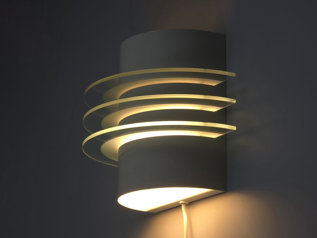 Lit Drittel lamp against a neutral wall, demonstrating the atmospheric uplight and downlight patterns.