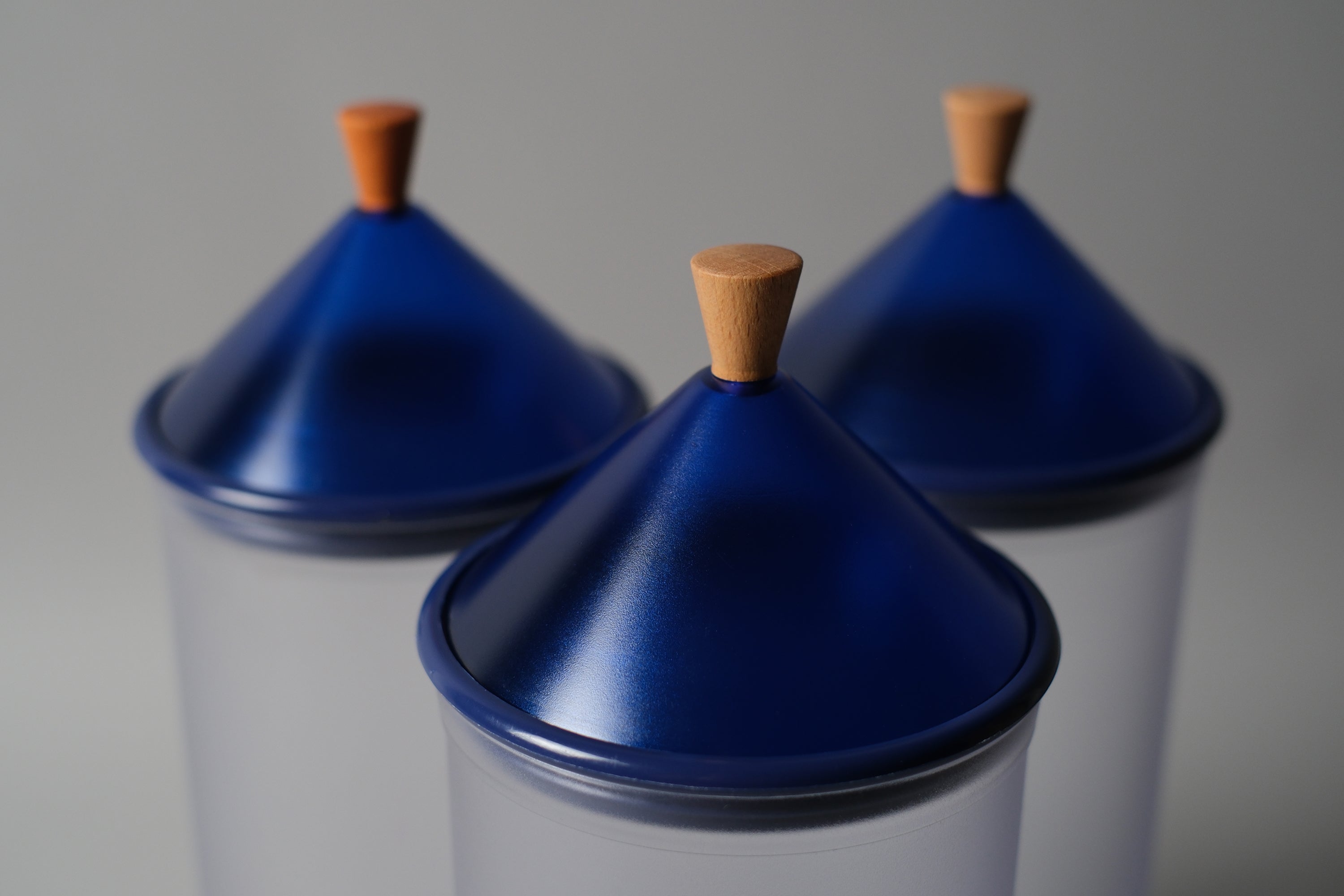 Close up of 3 blue plastic conical lids with wood handles of the Biesse canisters by Pino Spagnolo.