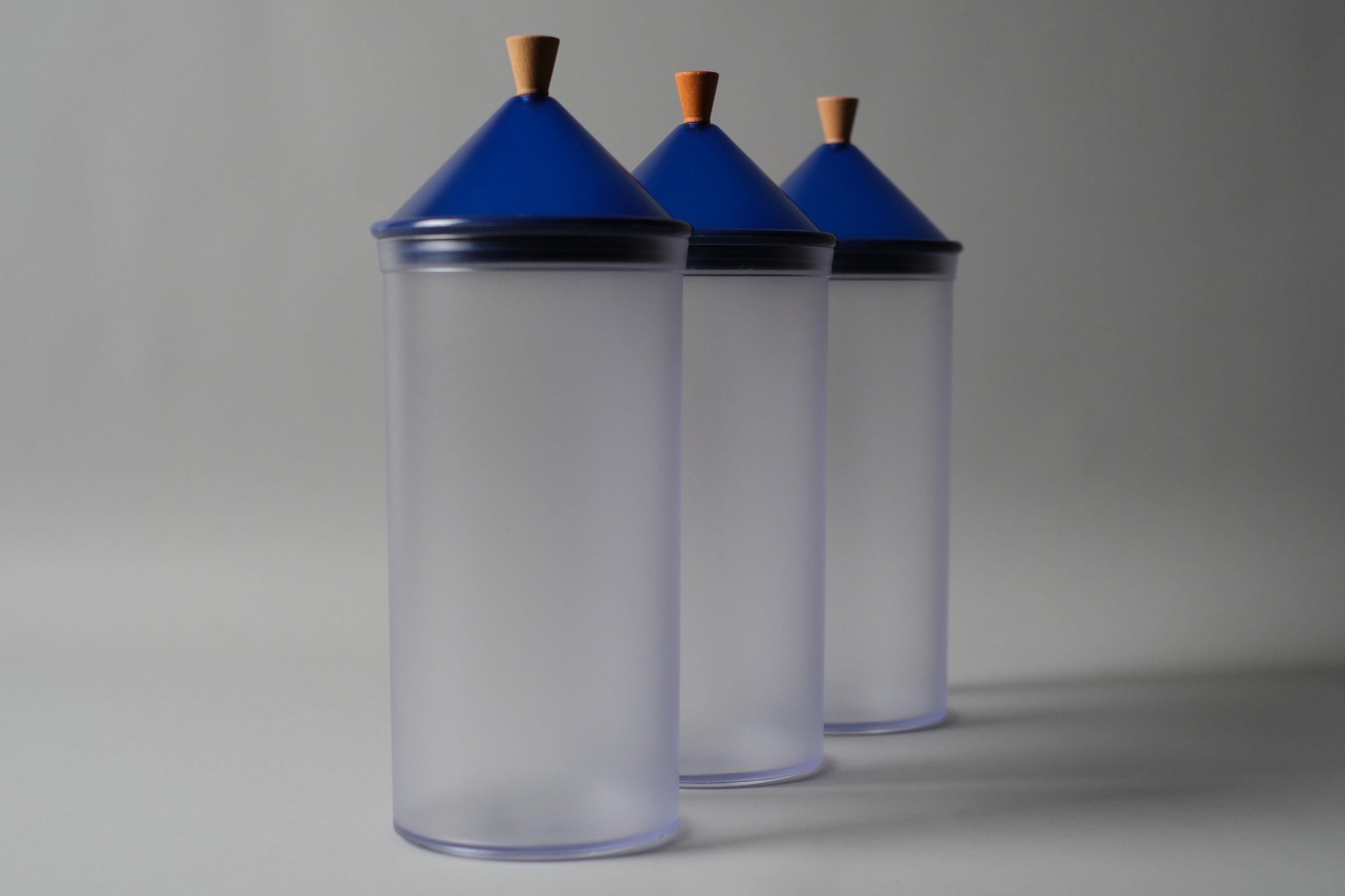 Set of 3 1980s 'Biesse Italy' postmodern plastic canisters by Pino Spagnolo. The jars have blue conical lids with wood handles.