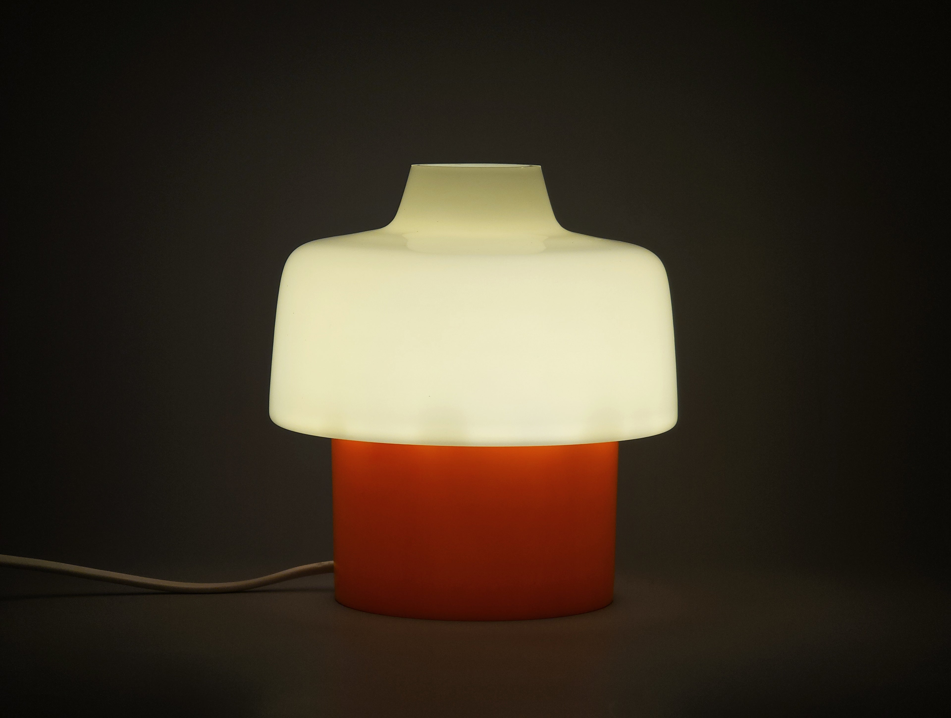 mcm bedside table lamp from the 1960 70s showing the glow of the glass shade