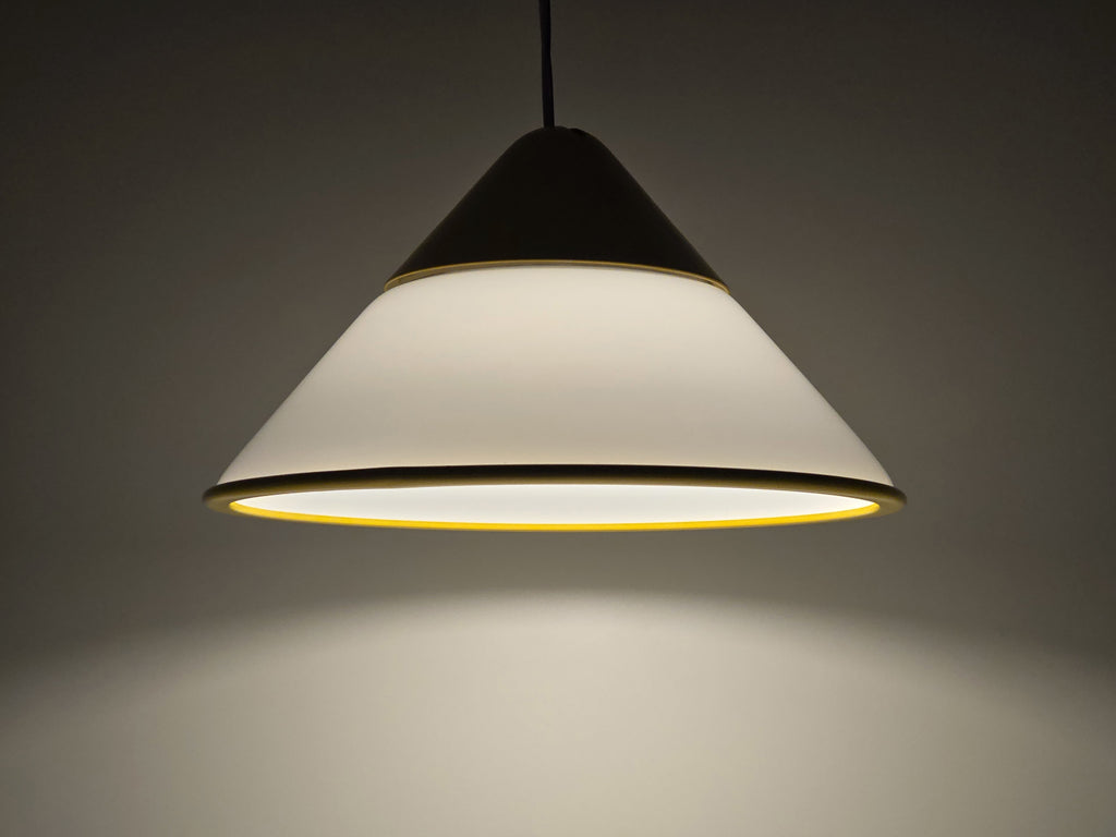 1980s Vintage Fabbian Italian opaline glass pendant lamp, Mid-Century Modern conical white opal hand-blown glass with yellow design details, showing the lamp lit with dark background.