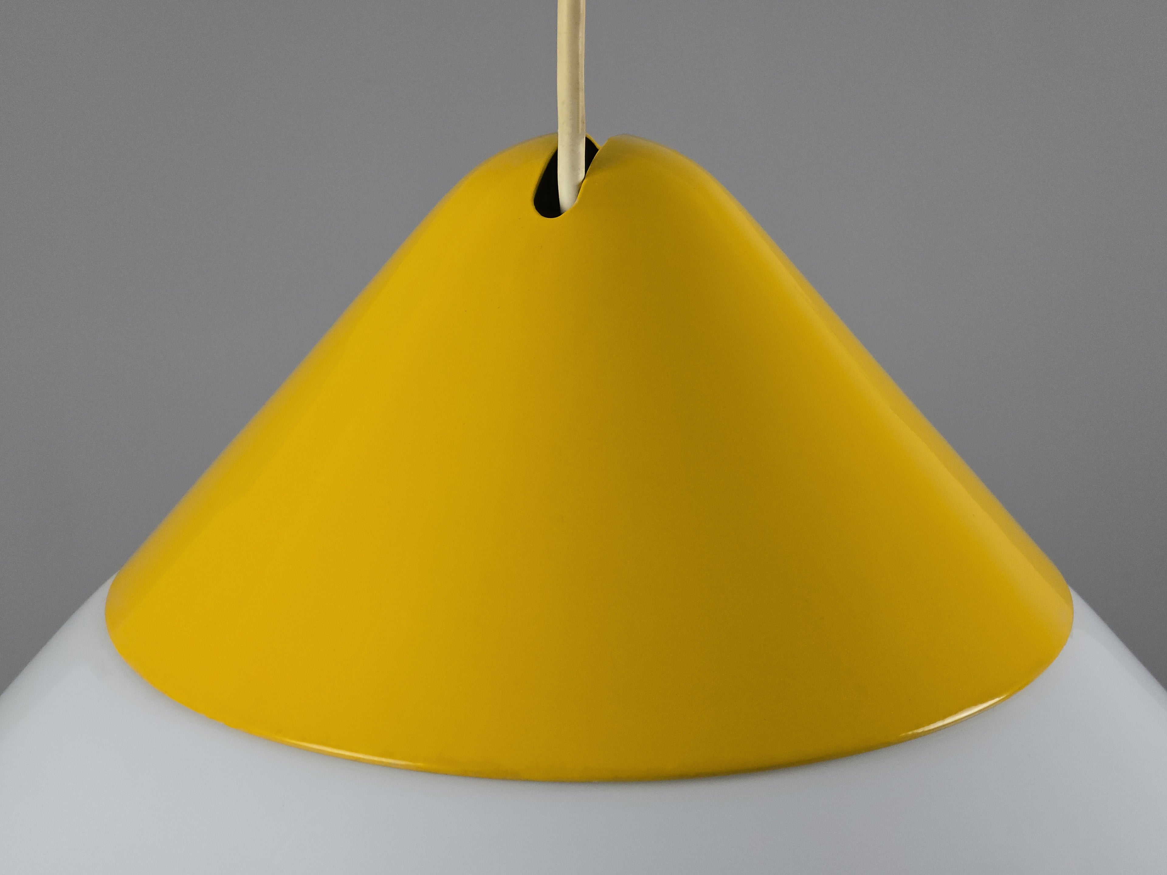 1980s Vintage Fabbian Italian opaline glass pendant lamp, Mid-Century Modern conical white opal hand-blown glass with yellow design details, showing yellow lacquered metal cap texture.