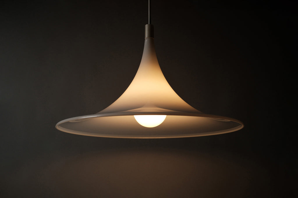 Front view of the 1970s Dijkstra heksenhoed pendant lamp fully illuminated, warm diffused light glowing through the white opaline acrylic shade