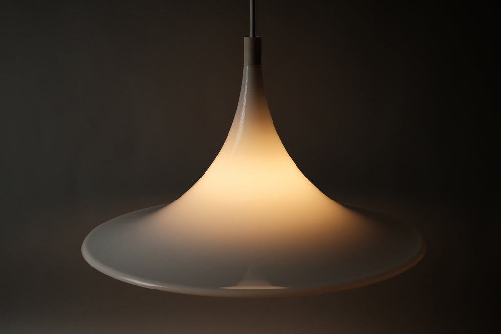 High angle view of the illuminated Dijkstra heksenhoed pendant, showing warm light pooling through the acrylic shade from above