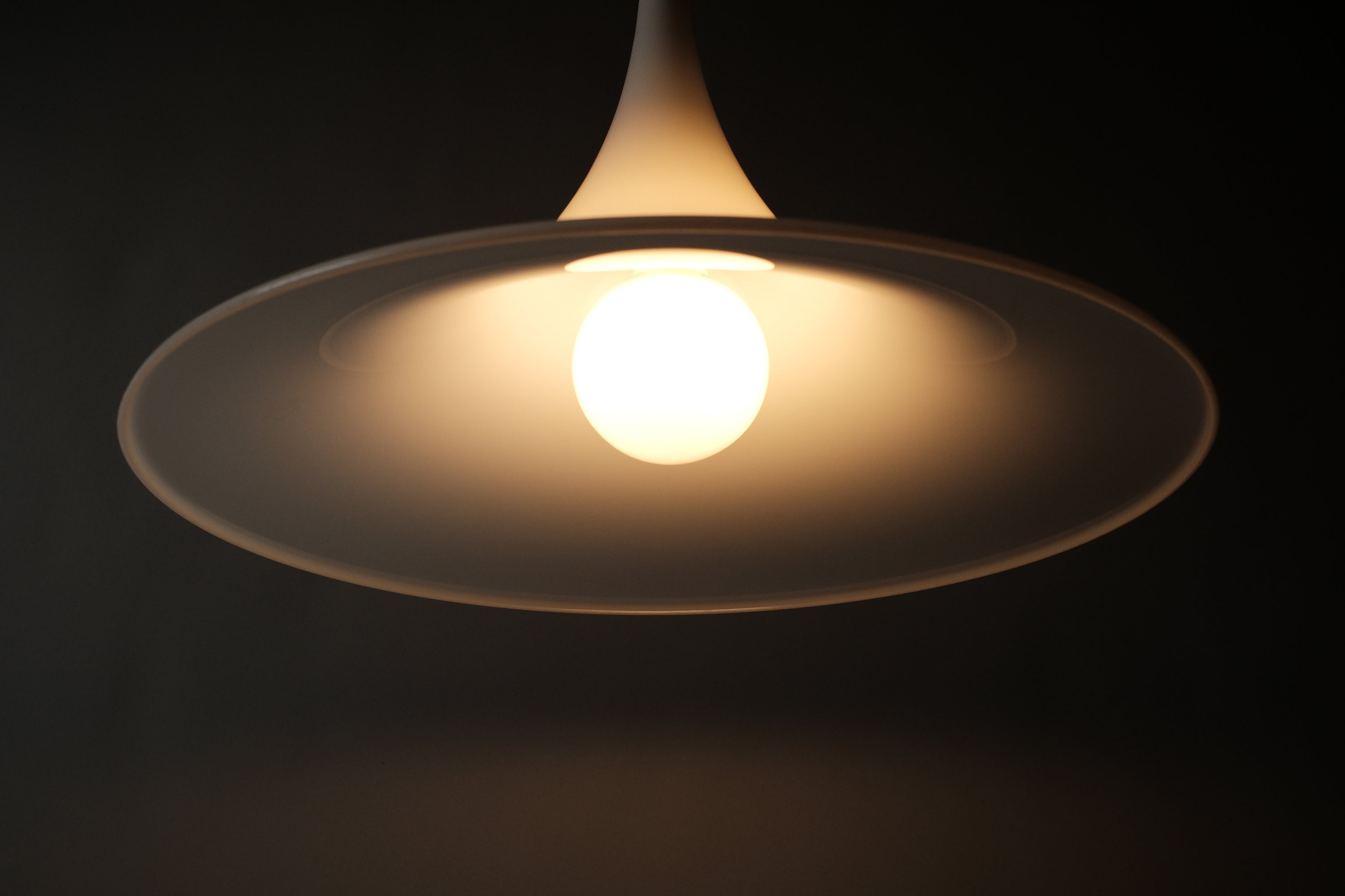 Dramatic low angle shot of the Dijkstra witch hat pendant fully lit, light scatter visible beneath the wide conical shade