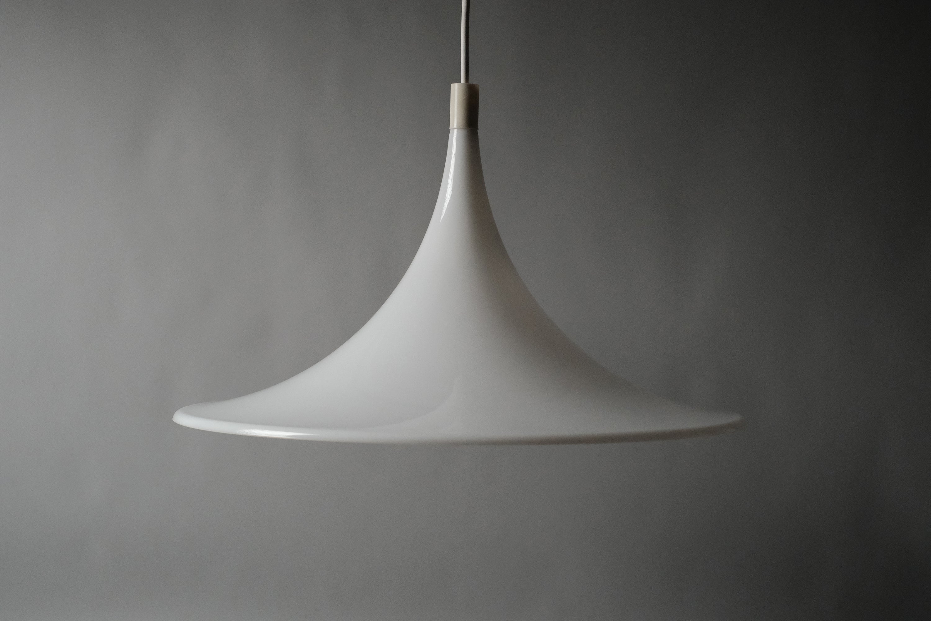 Front view of the 1970s Dijkstra Lampen white opaline acrylic heksenhoed pendant lamp, showing its sweeping conical witch hat silhouette against a grey backdrop