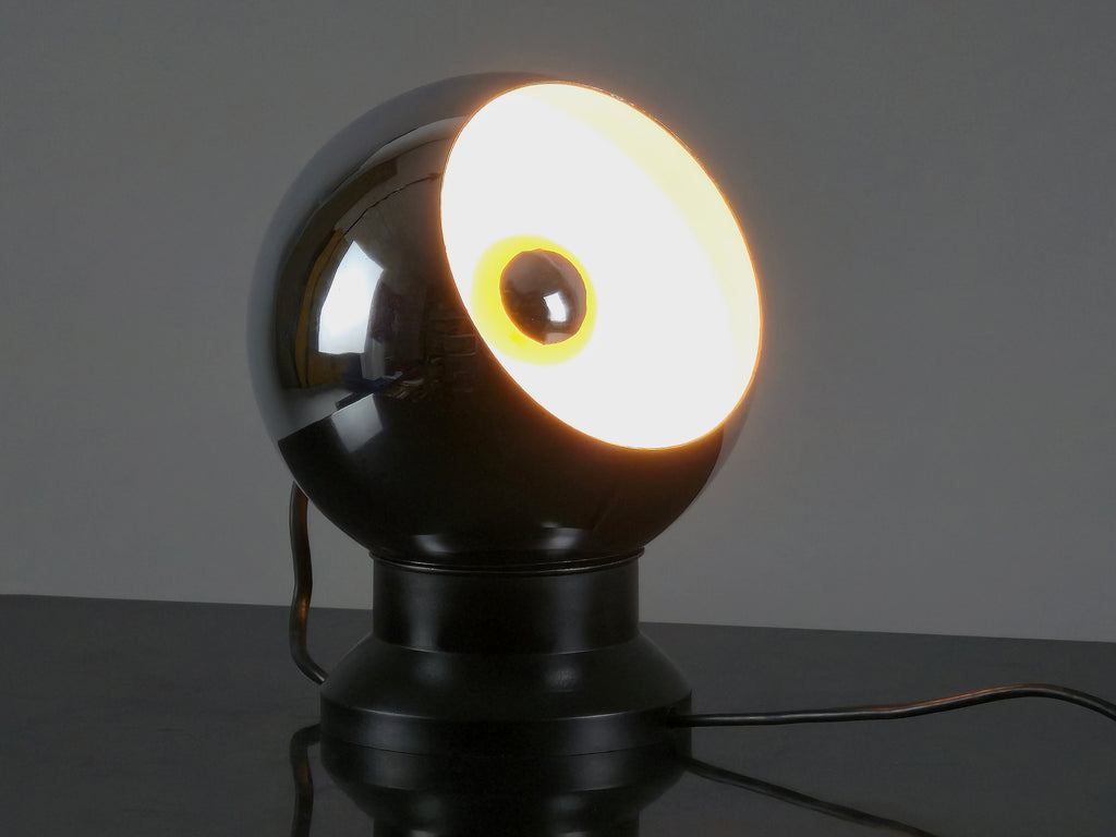 Angled view and lit in dark room of the vintage 1970s E.S. Horn magnetic ball lamp.
