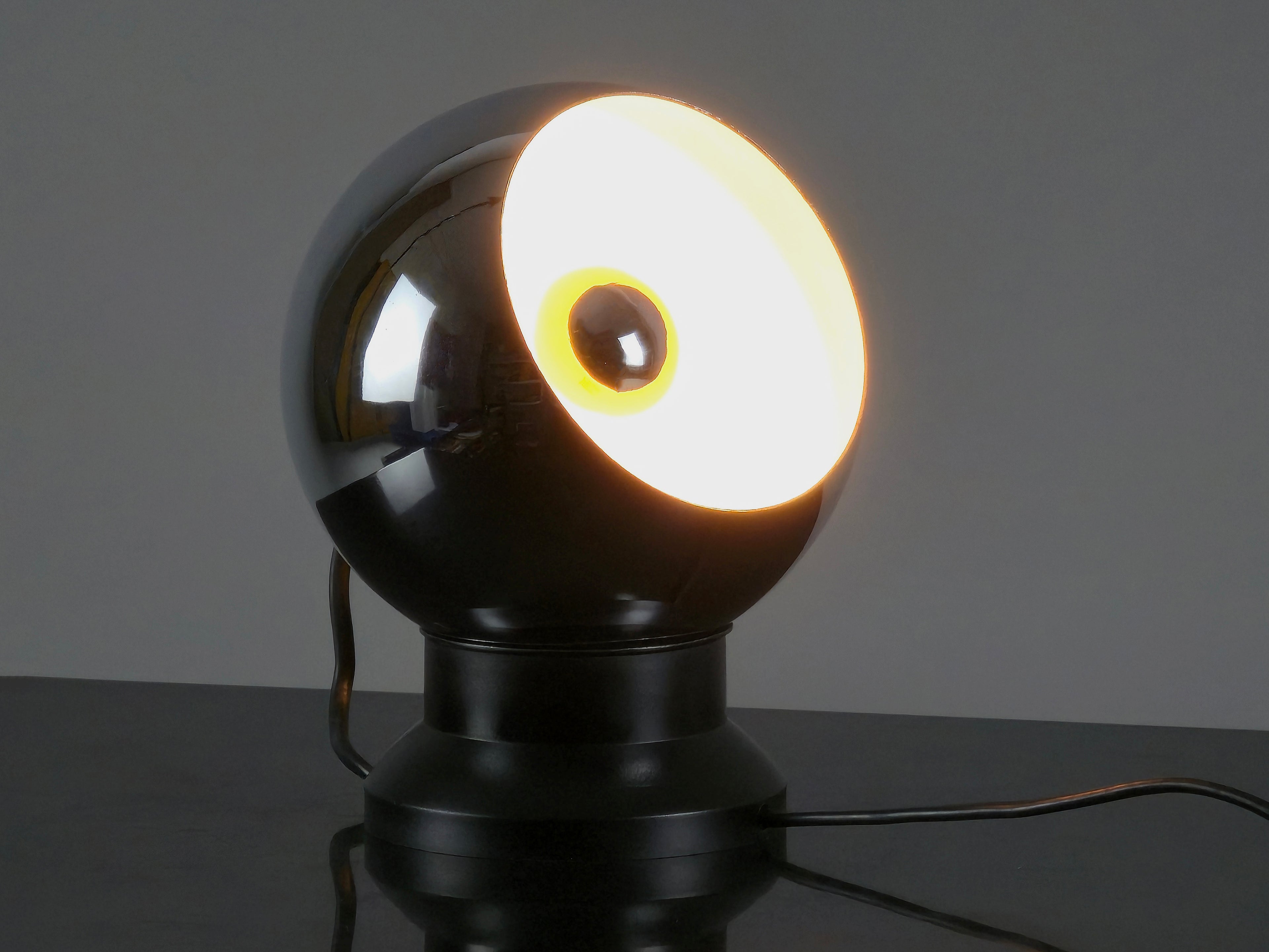 Angled view and lit in dark room of the vintage 1970s E.S. Horn magnetic ball lamp.