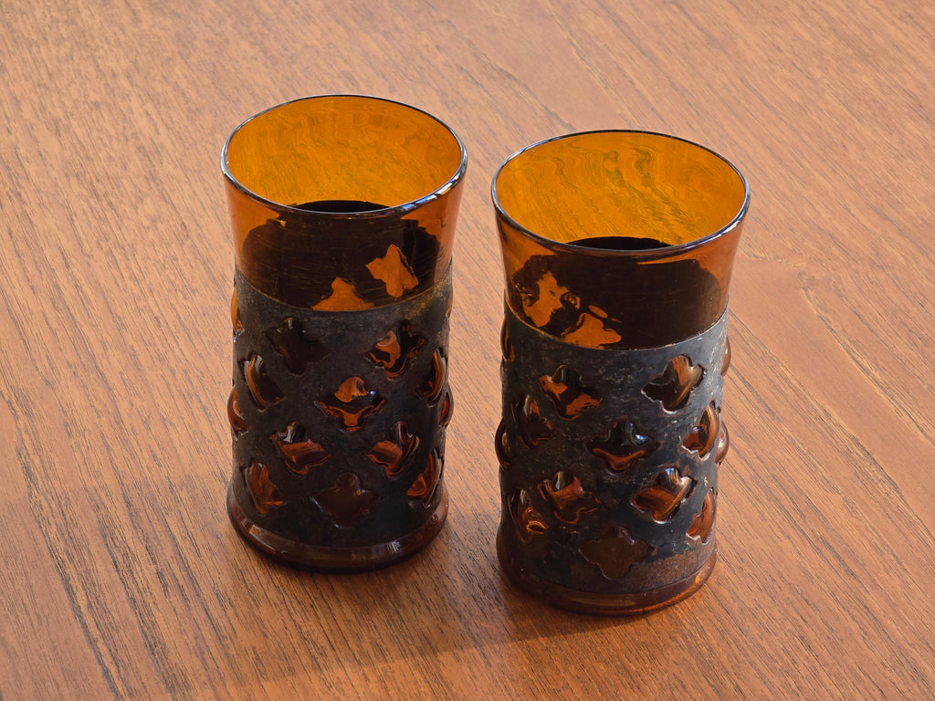 Atmospheric shot of the Brutalist glasses on a wooden surface, highlighting the play of light through the metal.