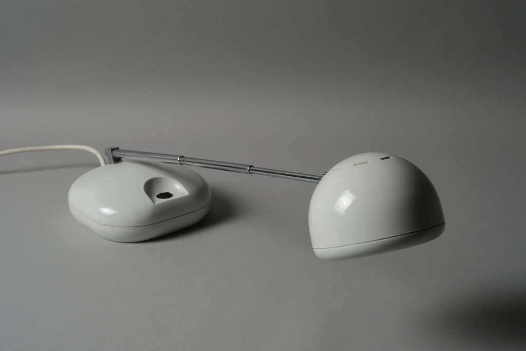 Low-angle view of a 1970s Hustadt Leuchten antenna halogen desk lamp from West Germany, showing the oval weighted base and telescopic stem rising from ground level, Type 3184.