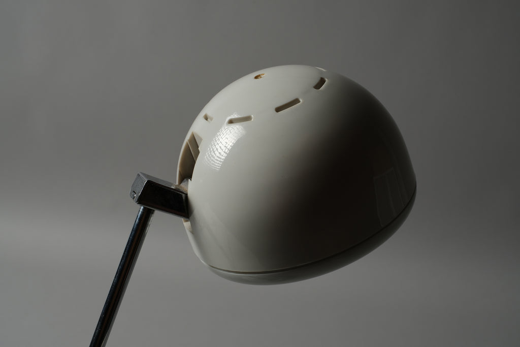 Macro detail of the spherical halogen spot head of a 1970s Hustadt Leuchten antenna desk lamp from West Germany, showing the rotating cup shade and ventilation slots on the white lacquered steel sphere.