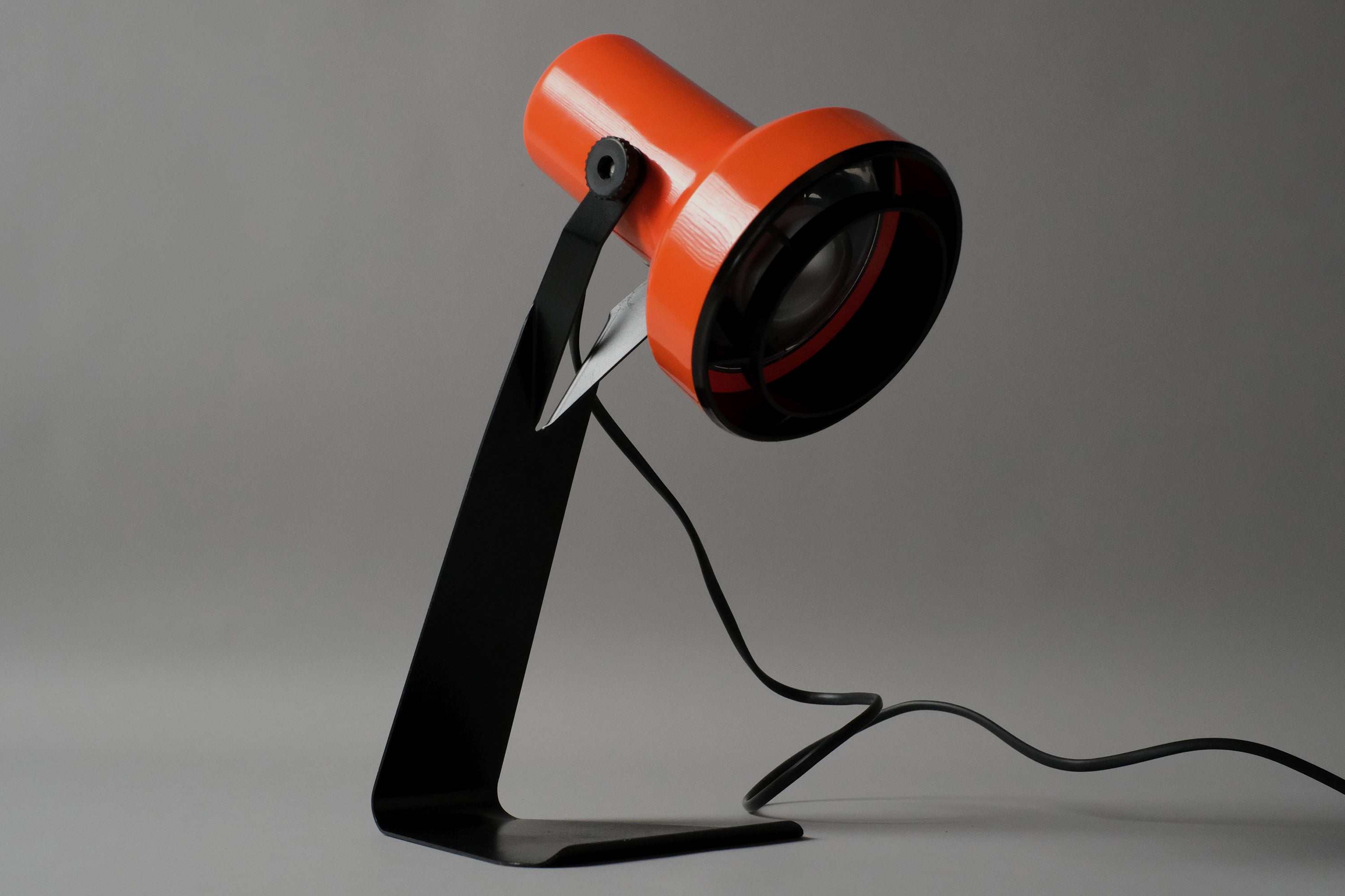 Front three quarter view of the rare 1970s Lyskaer Belysning Type 632 desk lamp, vivid orange plastic head contrasting against the angular matte black metal base
