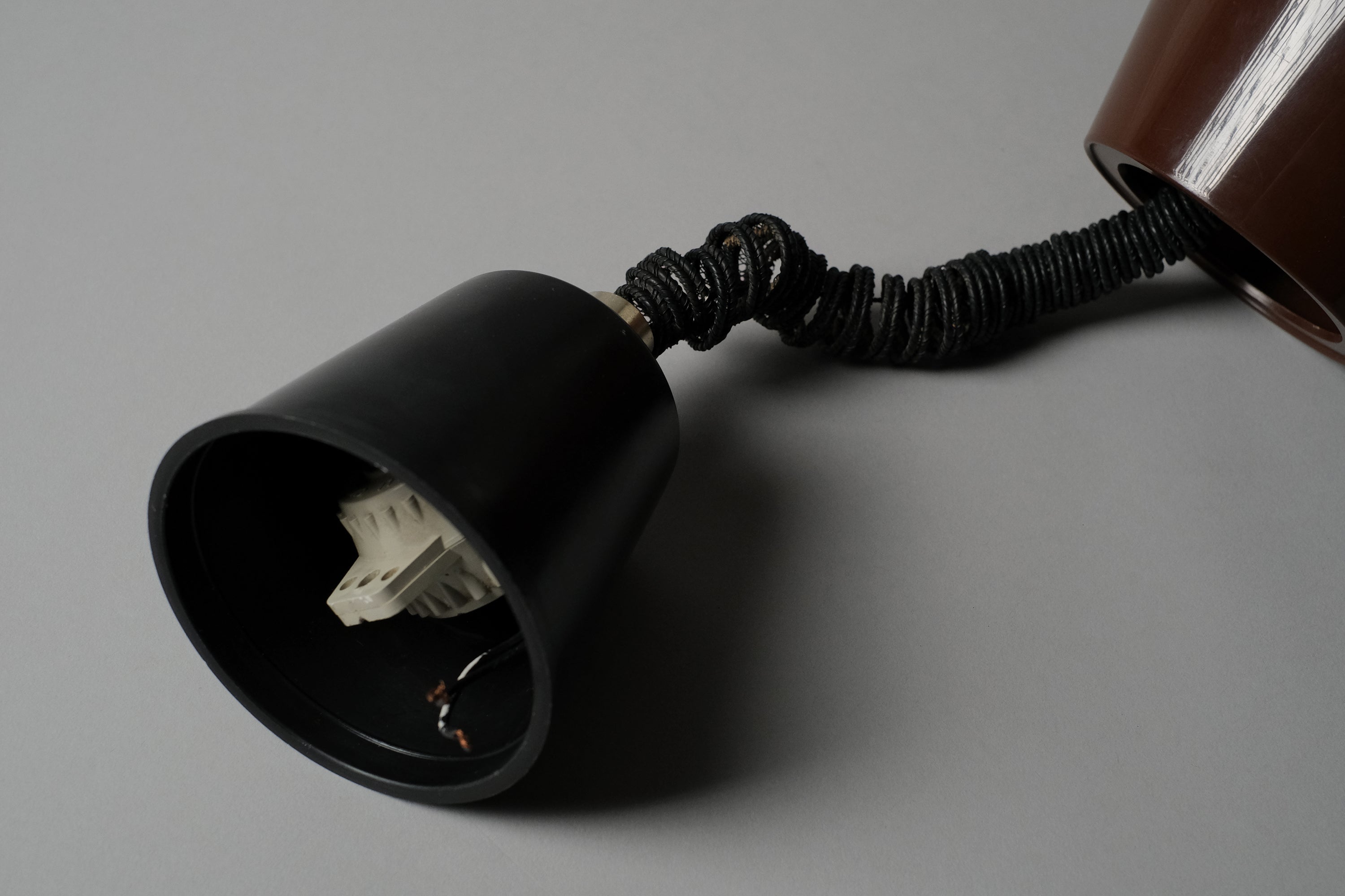 Close-up of the original ceiling cap and rise and fall rolly mechanism of a 1970s Massive Lighting Belgium UFO pendant lamp, showing the coiled cord and original hardware intact.