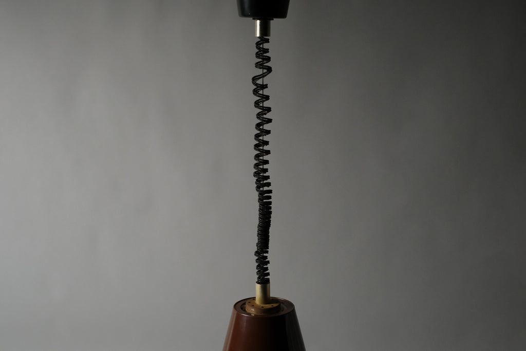 Full length view of the original coiled rise and fall cord of a 1970s Massive Lighting Belgium UFO pendant lamp, showing the complete suspension system from ceiling cap to shade.