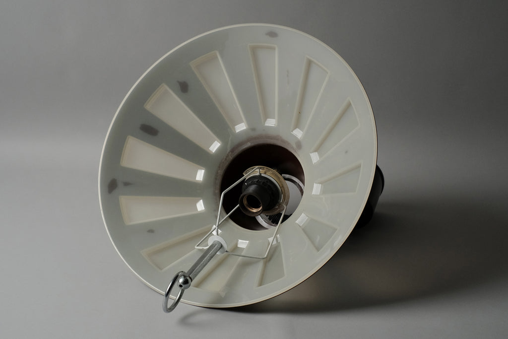 Interior view of a 1970s Massive Lighting Belgium UFO pendant lamp showing the translucent inner diffuser layer and original E27 fitting, with the geometric cutout pattern of the brown outer shell visible around the rim.