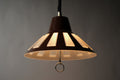 Front illuminated view of a 1970s Massive Lighting Belgium UFO pendant lamp, showing the warm striped light pattern produced by the brown outer ABS shell with geometric cutouts over the translucent inner diffuser.