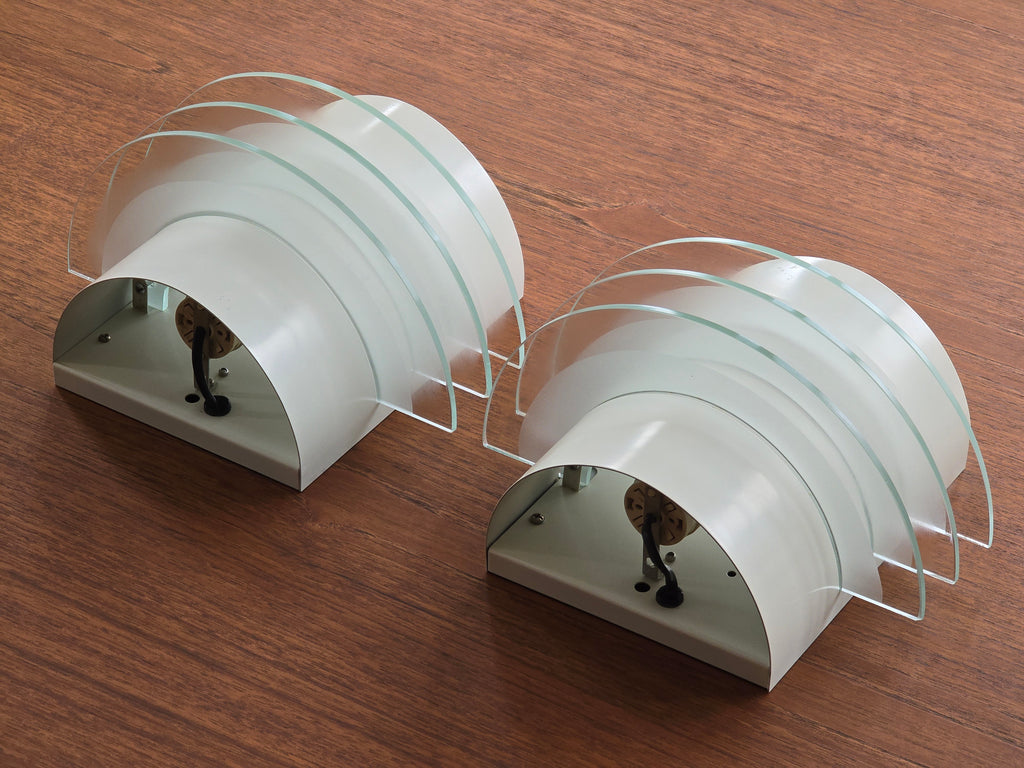 Perspective view of vintage 1992 pair of IKEA Drittel wall sconces with glass discs, laid on a teak wood table.