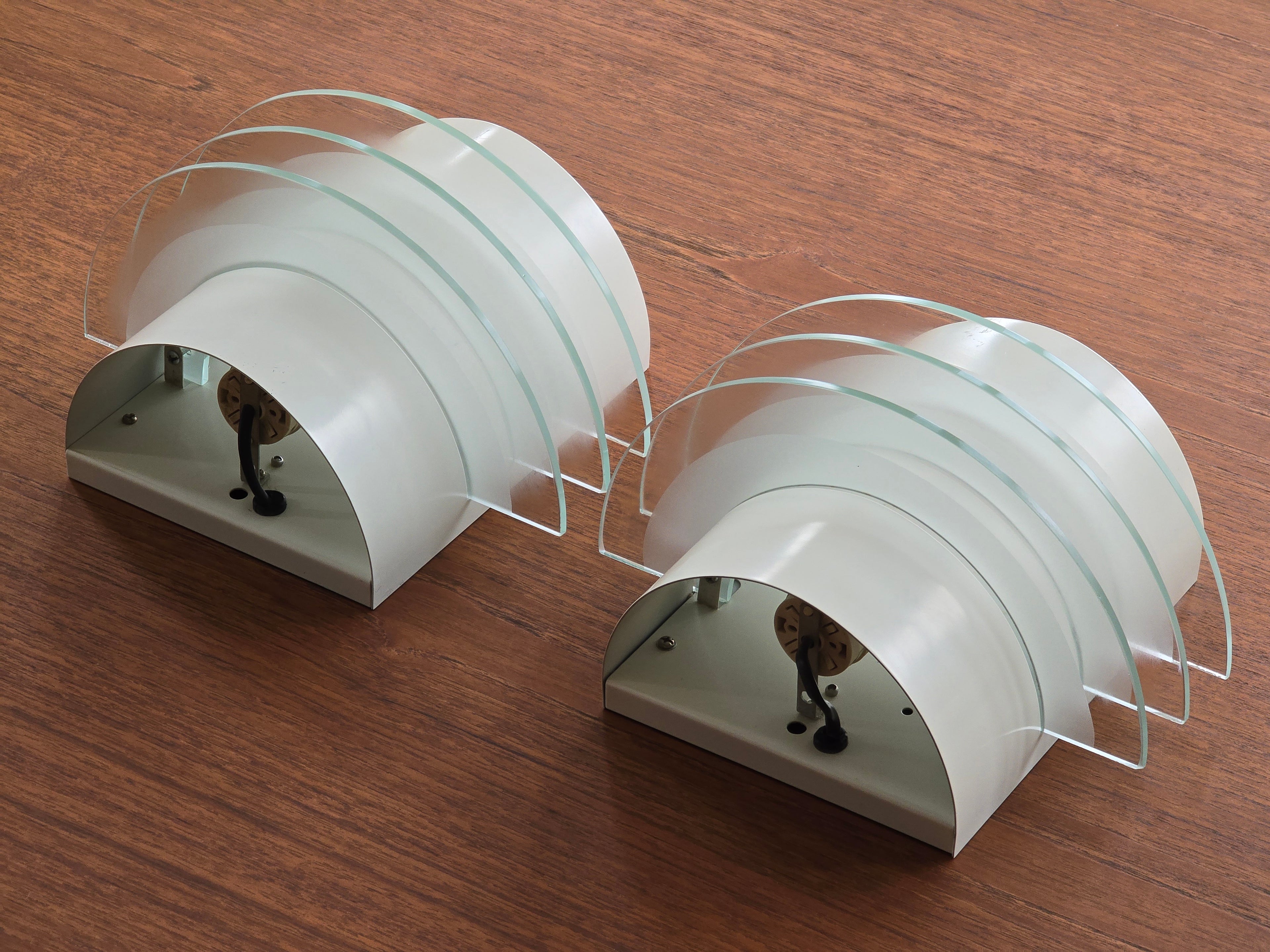 Perspective view of vintage 1992 pair of IKEA Drittel wall sconces with glass discs, laid on a teak wood table.