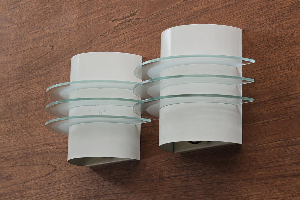 Vintage 1992 pair of IKEA Drittel wall sconces with glass discs, wall mounted on a teak wood wall.