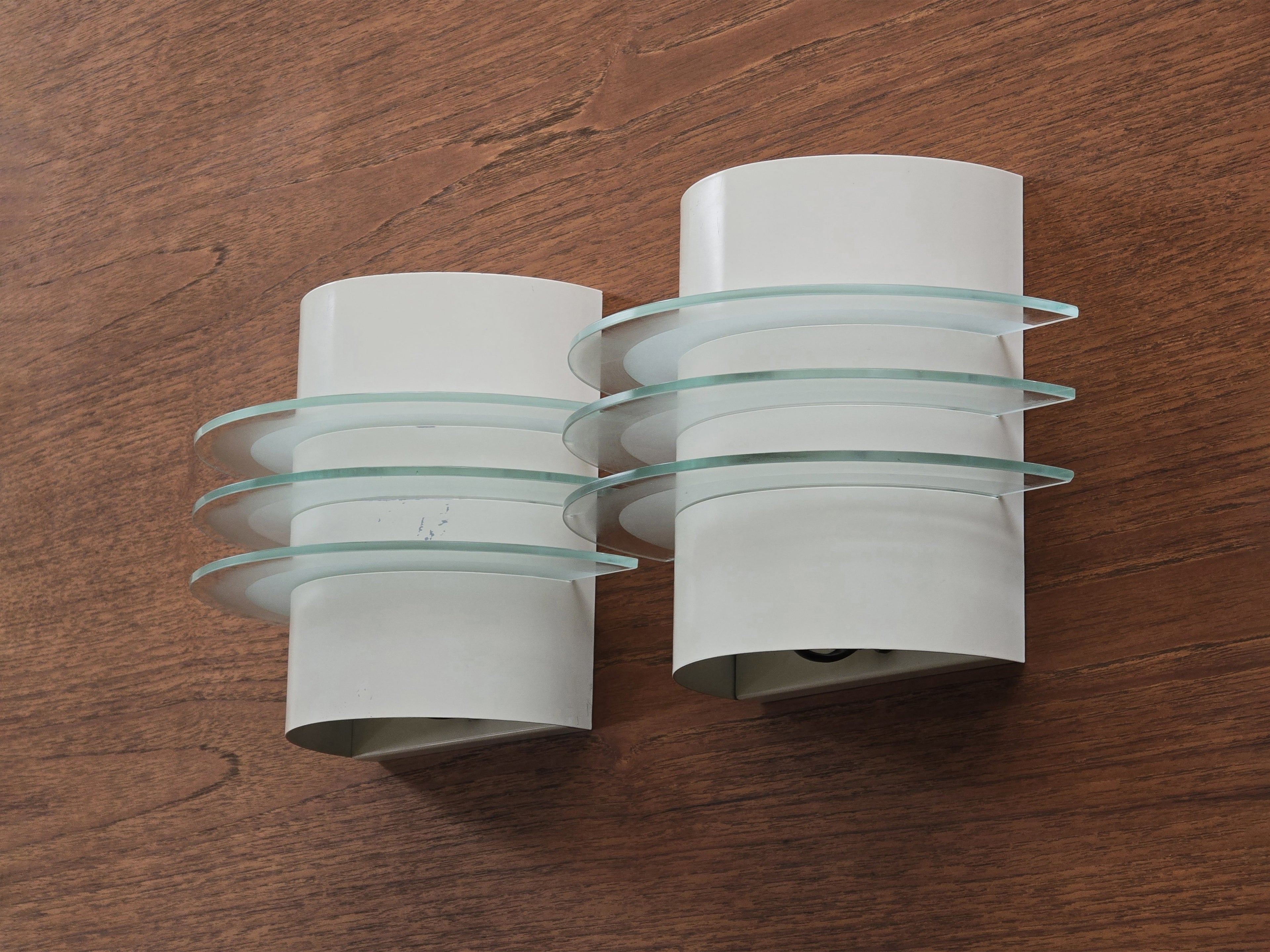 Vintage 1992 pair of IKEA Drittel wall sconces with glass discs, wall mounted on a teak wood wall.