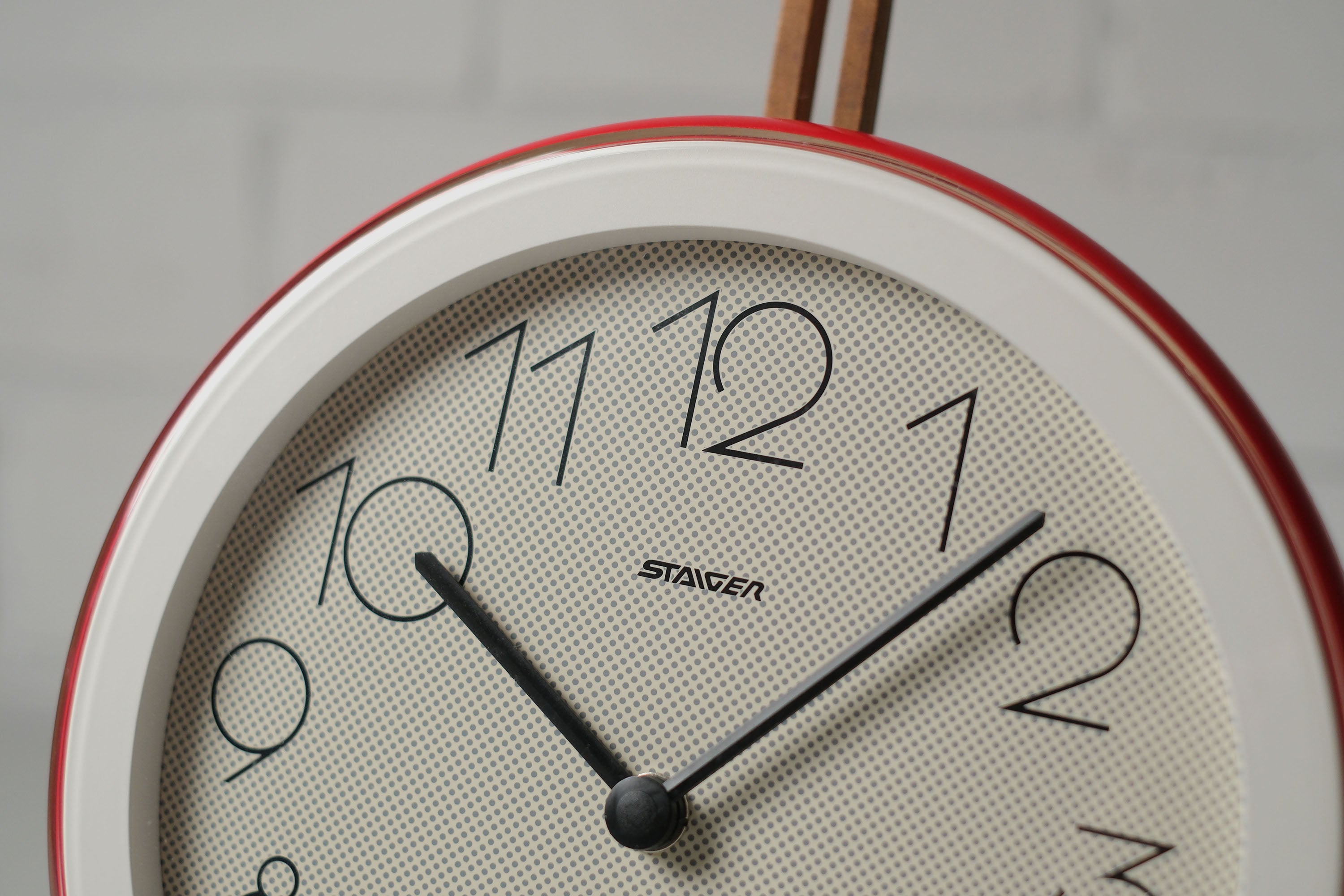 Close up detail of the upper half of a vintage 1980s postmodern round wall clock by Staiger West Germany with pop-art dotted face, red and white plastic frame.