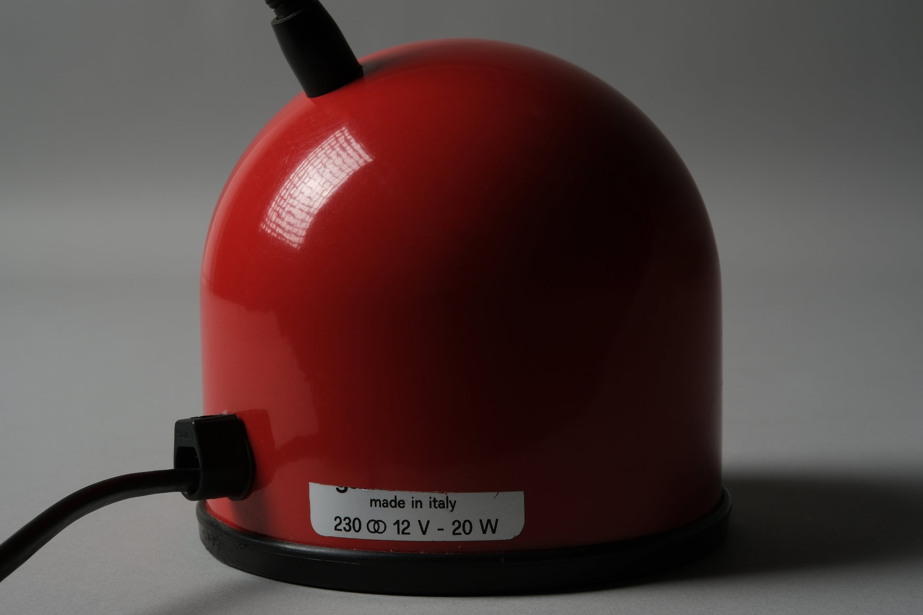 Detail view of the red ABS dome base and manufacturer label of a 1980s Stilplast flexible halogen desk lamp from Italy, showing the Stilplast brand marking and electrical specifications.